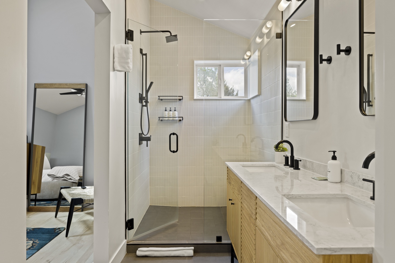 Refresh in your sleek ensuite bathroom featuring a spacious glass shower, marble countertops, and modern black fixtures.