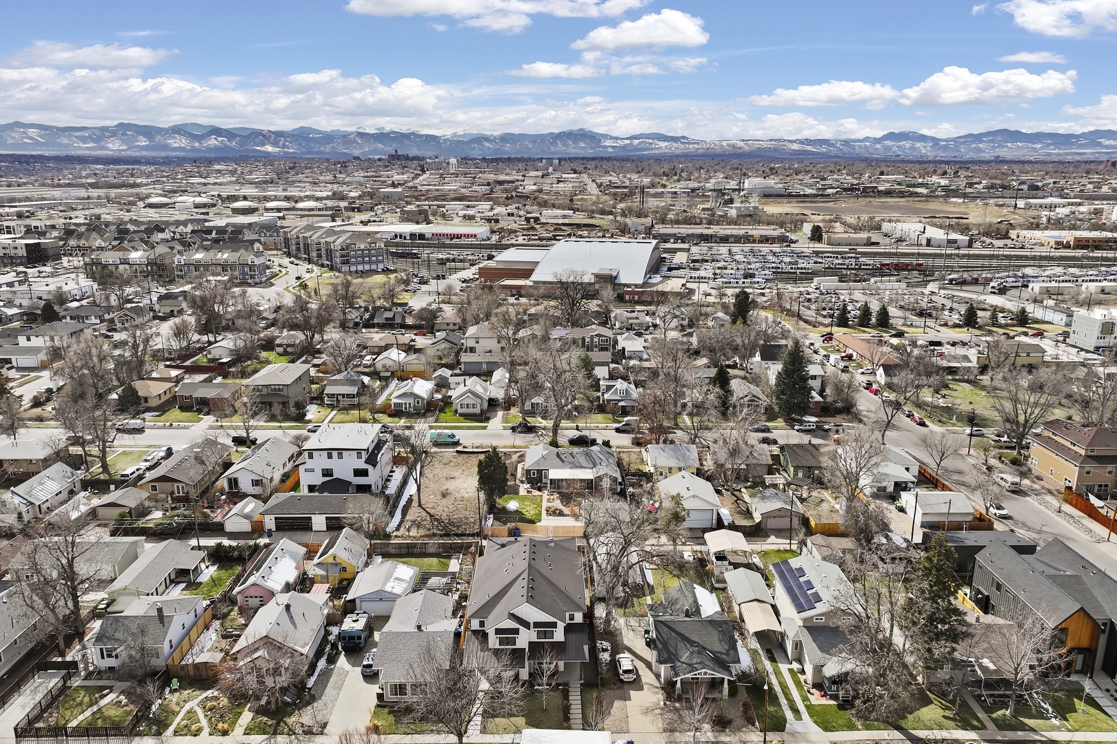 Aerial view captures a charming residential neighborhood with mountains creating a stunning backdrop for the surrounding area.