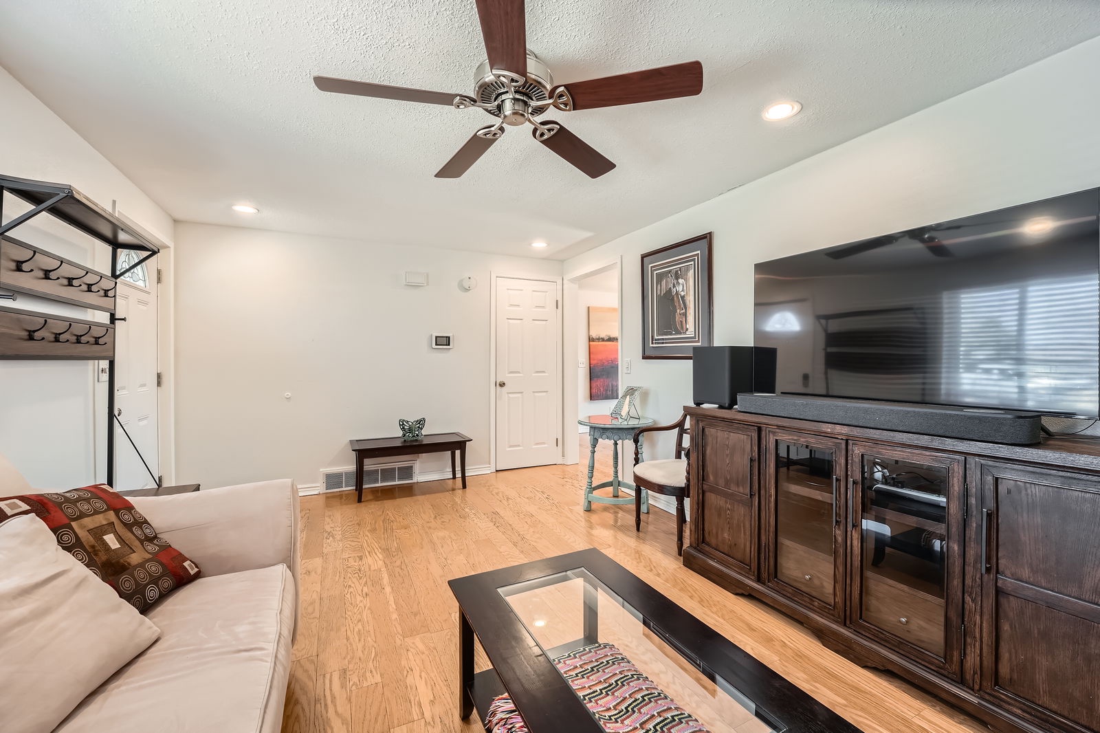 Unwind in your spacious living room with cozy seating, entertainment center, and ceiling fan for perfect comfort.