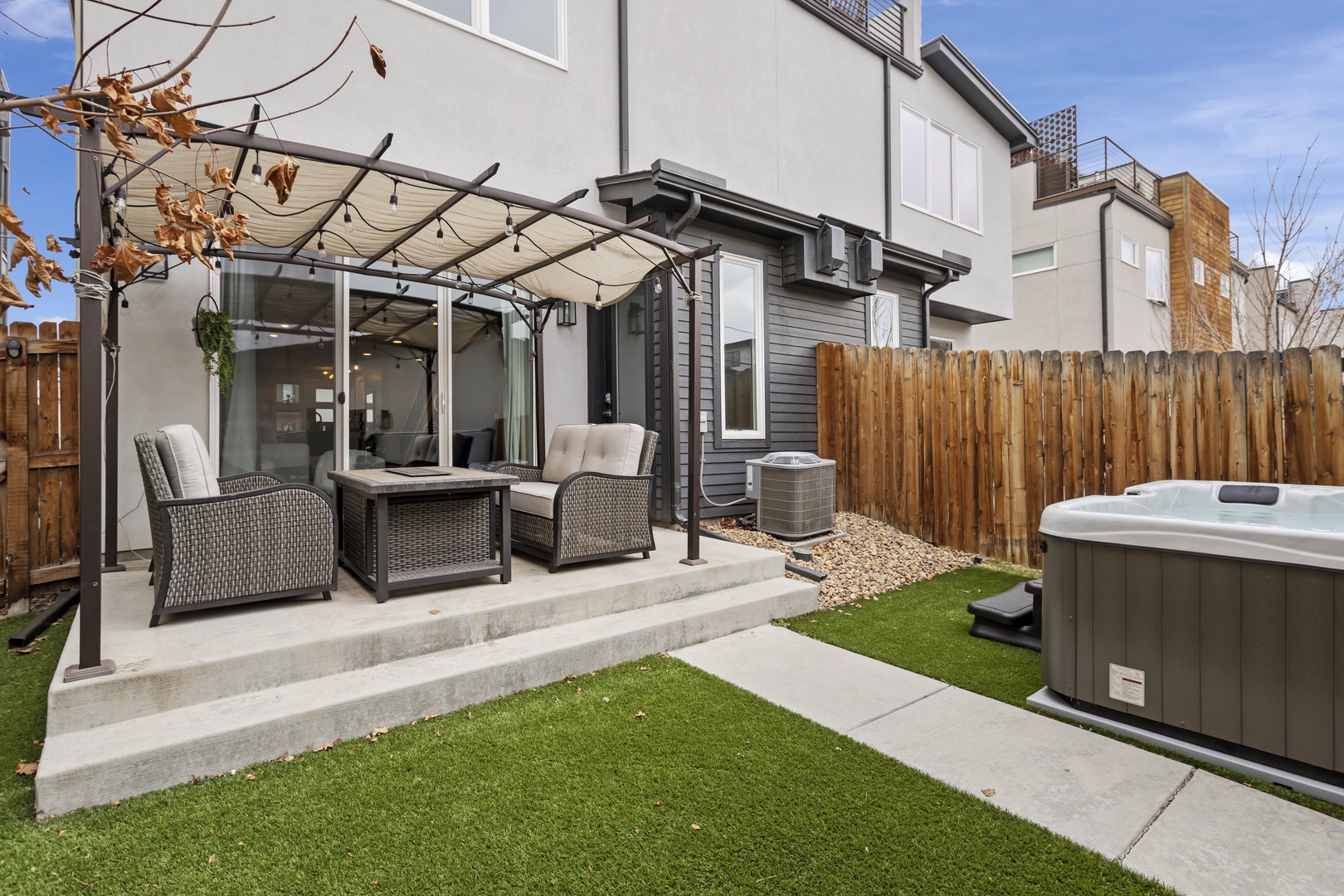 Your private backyard oasis features a covered patio with comfortable seating and a relaxing hot tub for ultimate outdoor enjoyment.