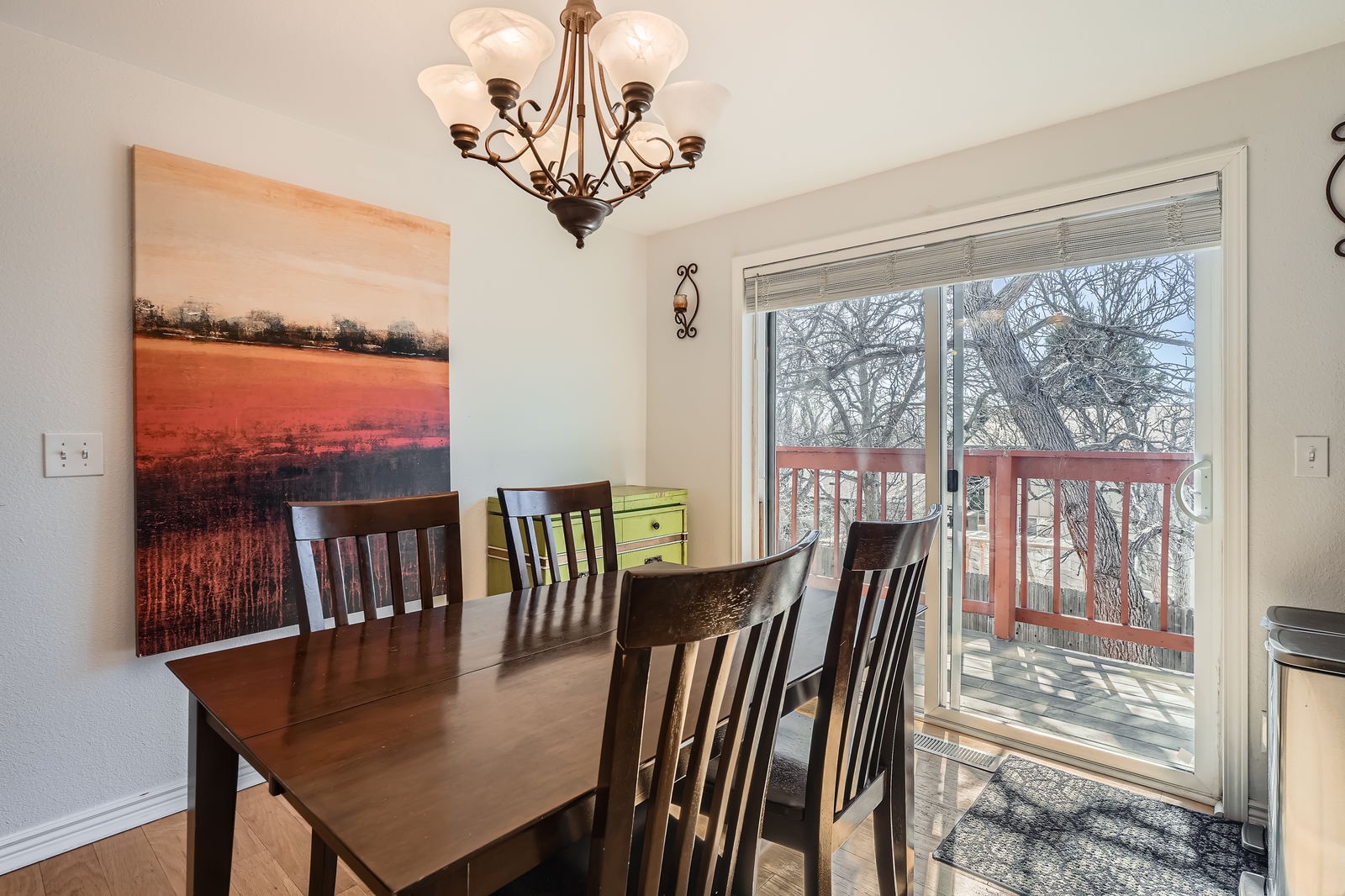 Gather around your elegant dining table under warm chandelier light, with beautiful tree views through sliding doors to your private deck.