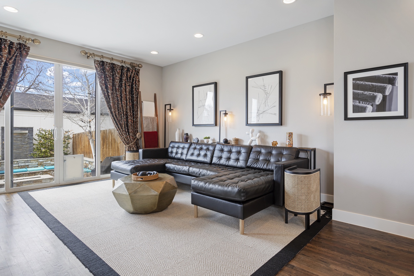 Relax in your sophisticated living room featuring leather seating and pool views through oversized windows.