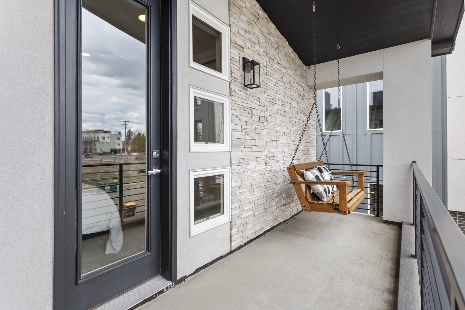 Relax on your private balcony's charming wooden swing, where modern design meets cozy comfort for perfect afternoon retreats.