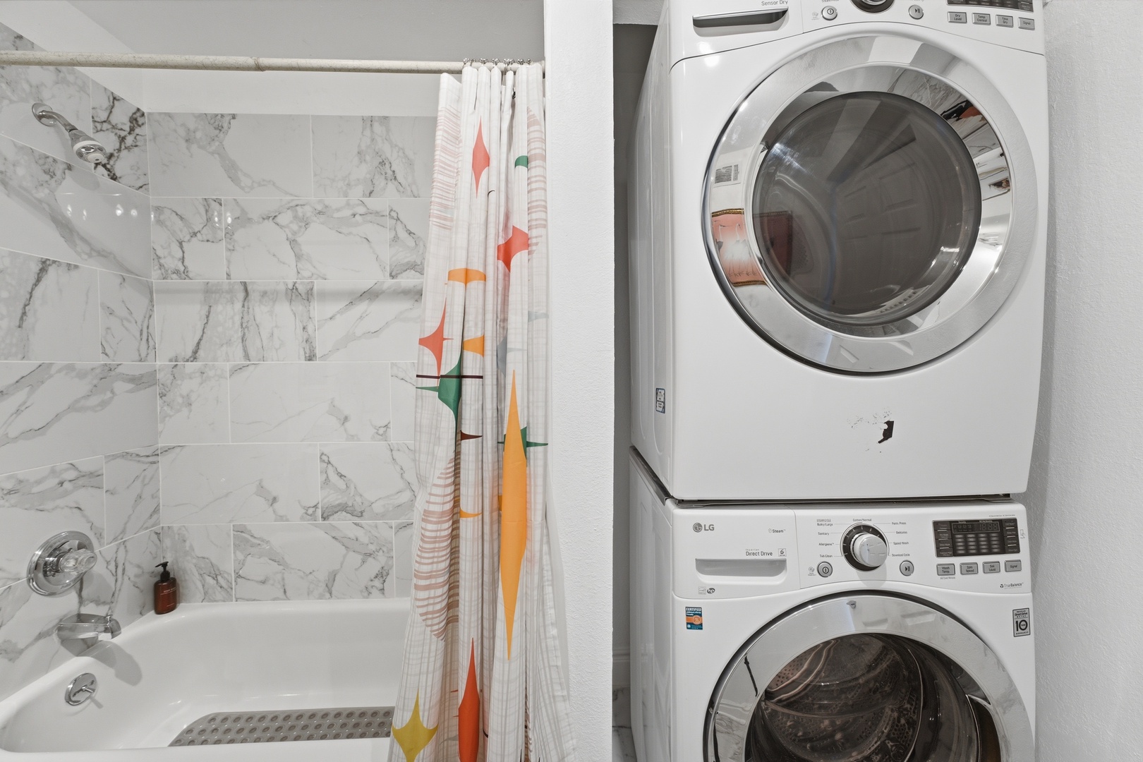 Your private bathroom features a full tub-shower combo with elegant marble-style tile, plus in-unit washer and dryer for ultimate convenience during your stay.