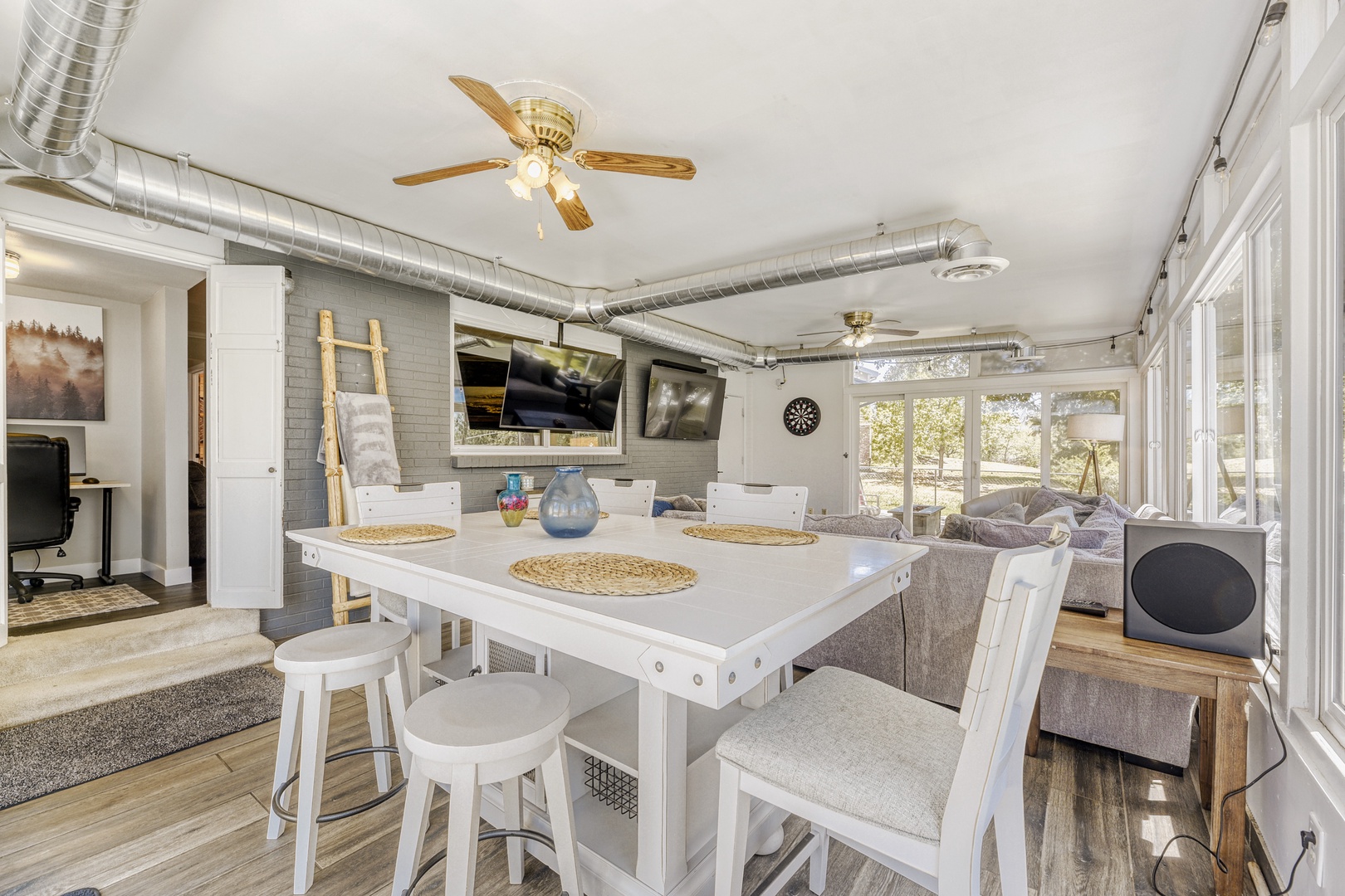 Gather around the bright dining table for meals or board games, with ceiling fans keeping you comfortable and views of the natural surroundings through large windows.