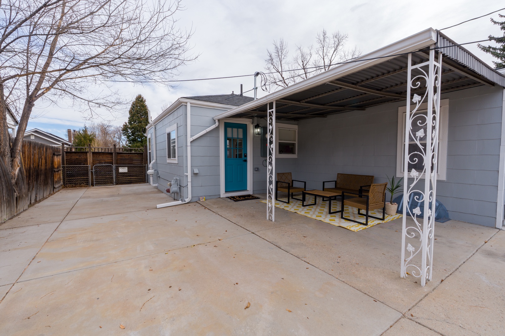 A charming property facade featuring a welcoming turquoise door and covered patio seating area perfect for relaxing outdoors.