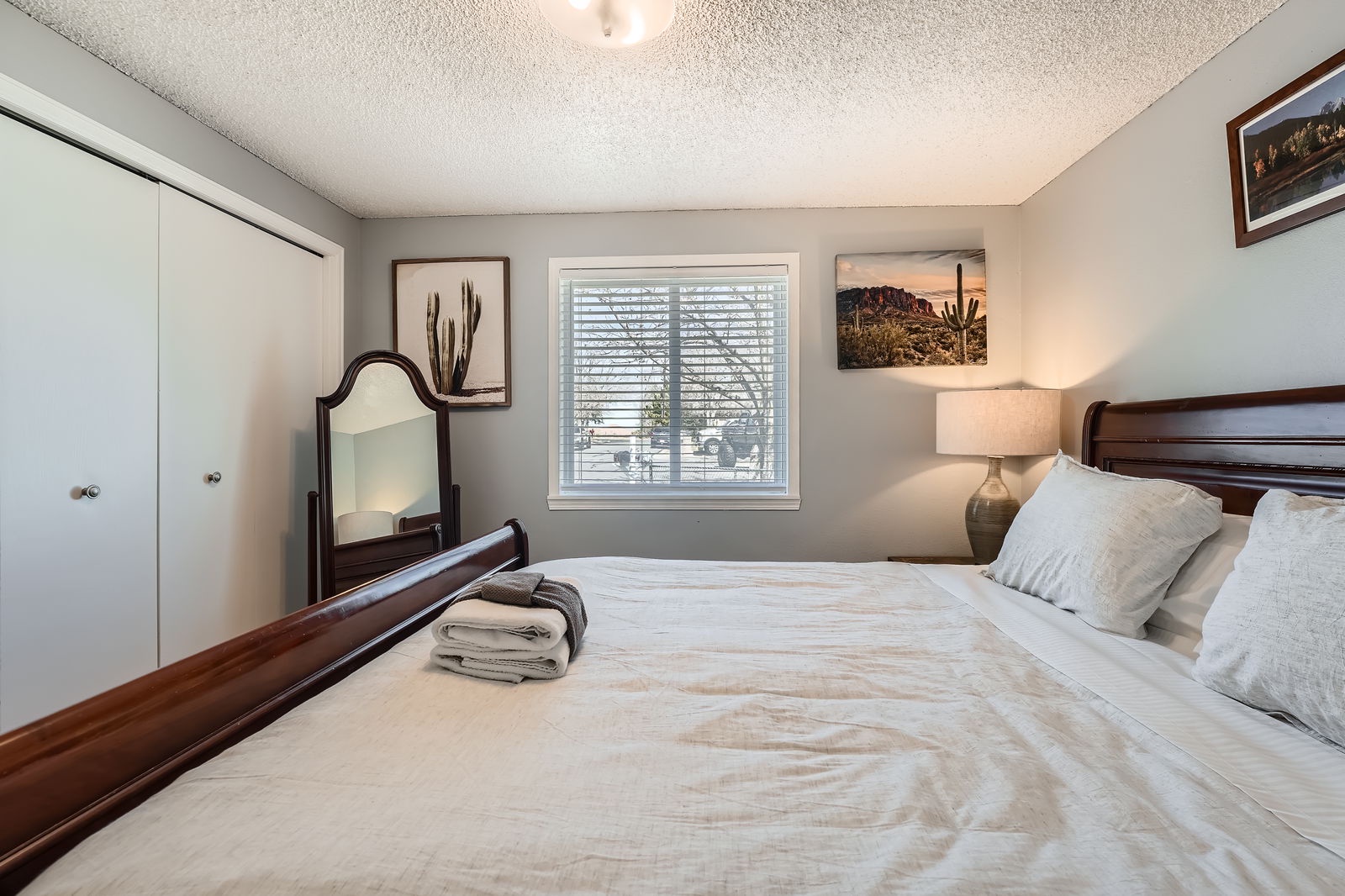 Unwind in your peaceful bedroom featuring elegant dark wood furnishings, crisp linens, and thoughtful desert artwork that creates a serene retreat for restful nights.