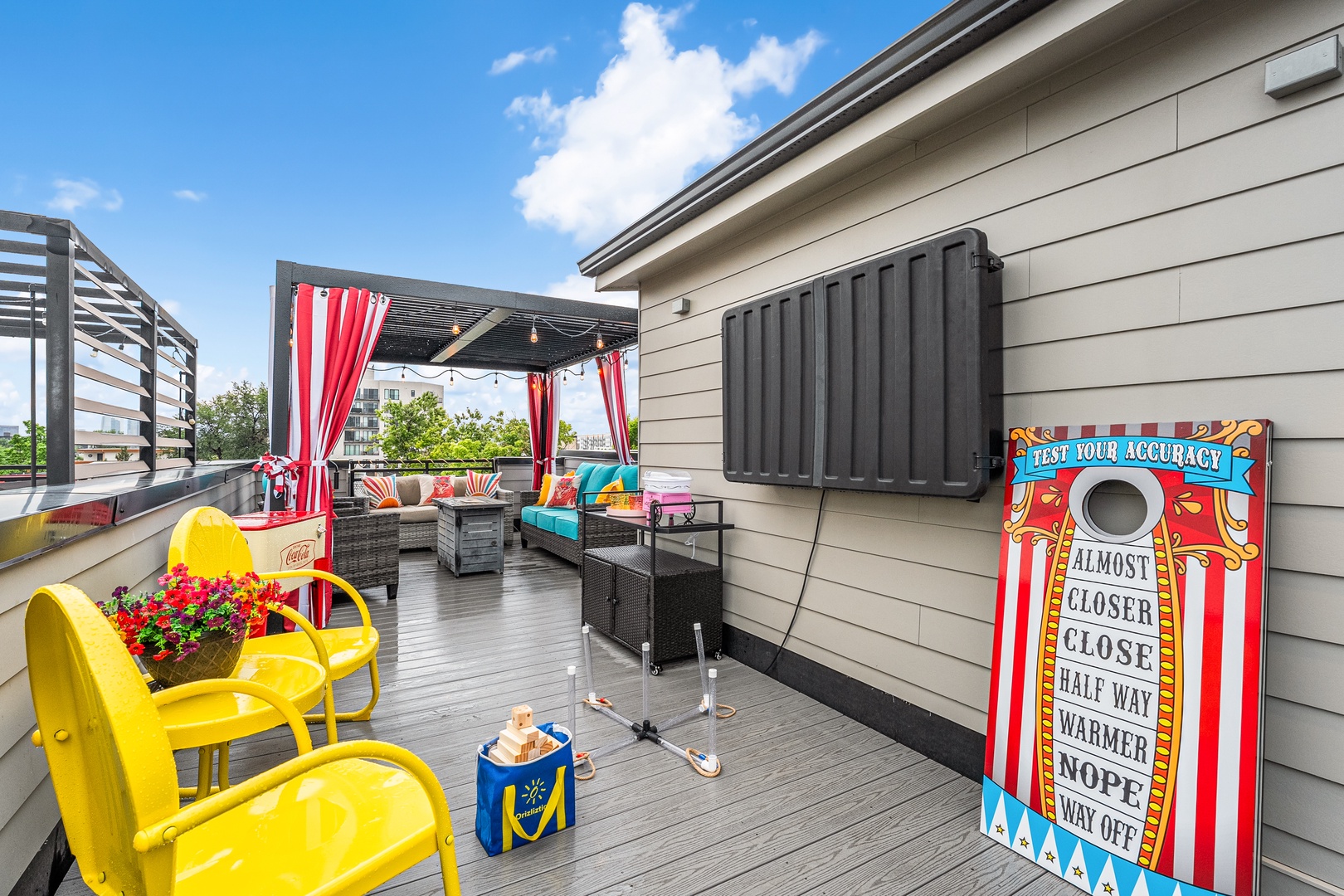 Private rooftop deck with playful cornhole, covered lounge seating, and open-air entertaining space—perfect for summer gatherings, relaxing sunsets, and quality time with loved ones.