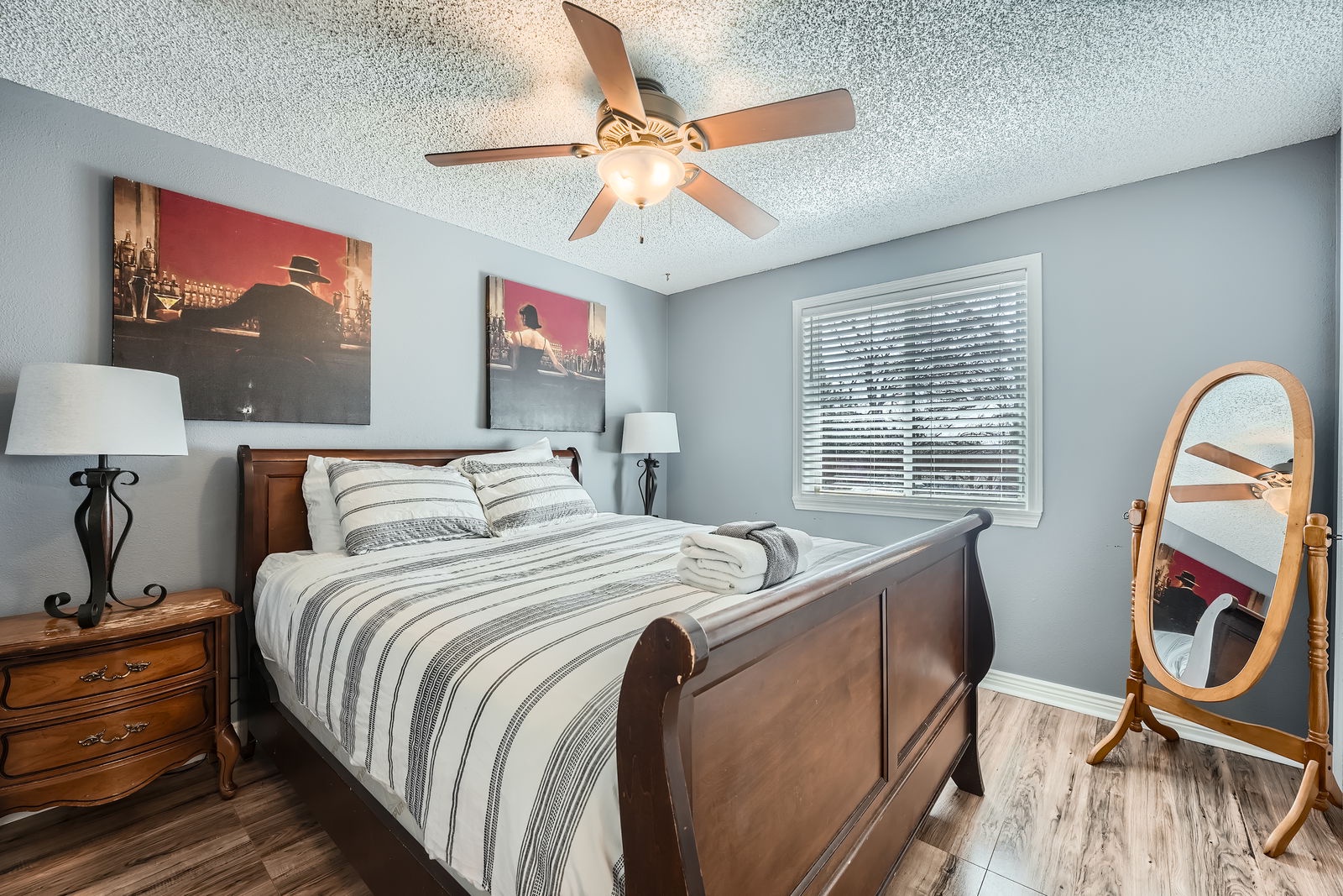 Your comfortable bedroom features a stylish wooden sleigh bed with plush linens and a ceiling fan for perfect temperature control.