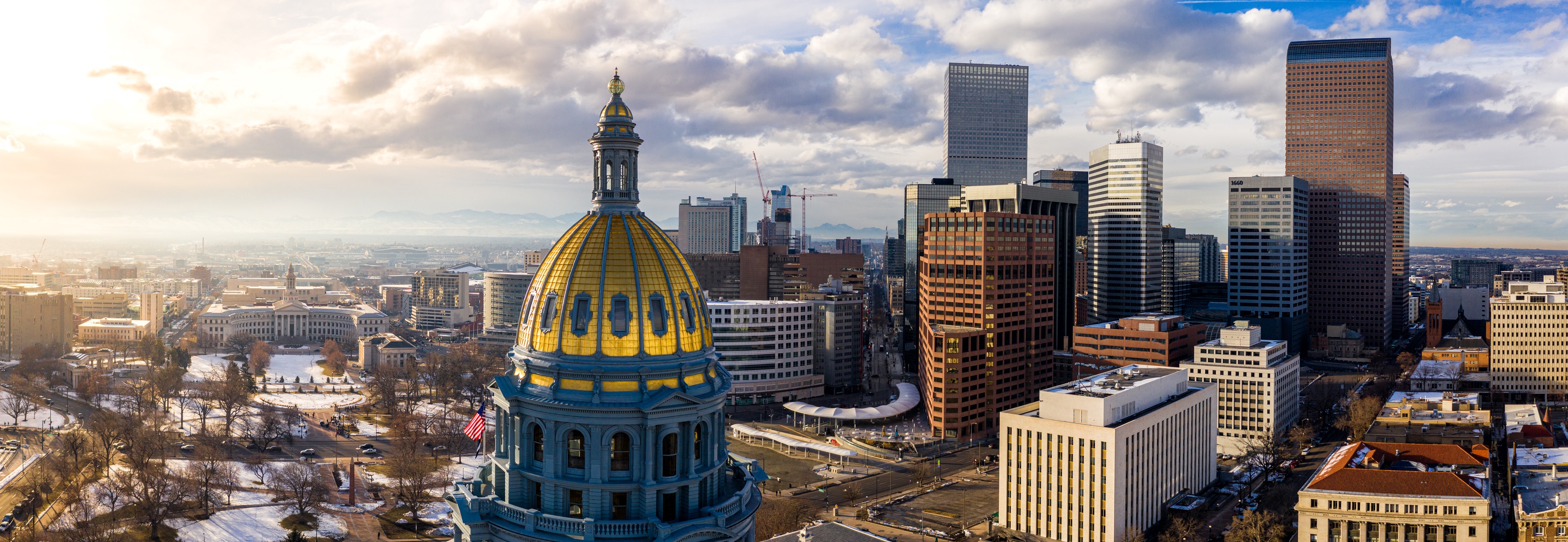 Denver's iconic gold-domed State Capitol anchors this stunning cityscape view, showcasing the vibrant downtown skyline and mountain backdrop.