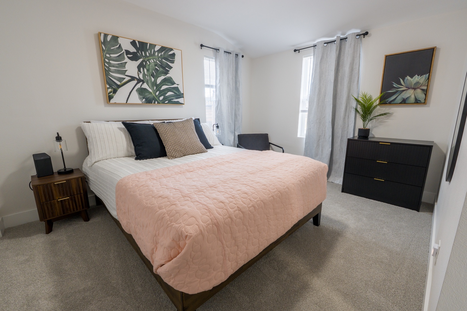 Drift into peaceful sleep in your stylish bedroom featuring a cozy queen bed with soft pink linens and tropical artwork creating a serene retreat.