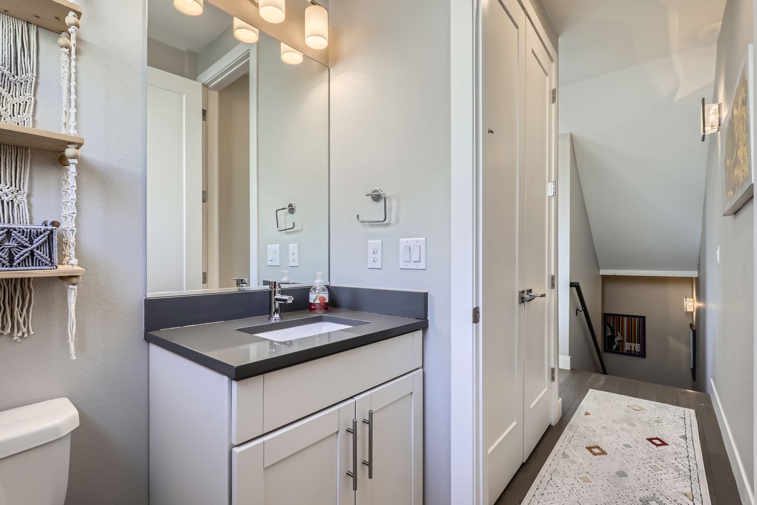 This bright bathroom offers a sleek vanity with warm lighting, plus thoughtful touches like fresh towels and coastal décor to help you unwind after exploring the area.