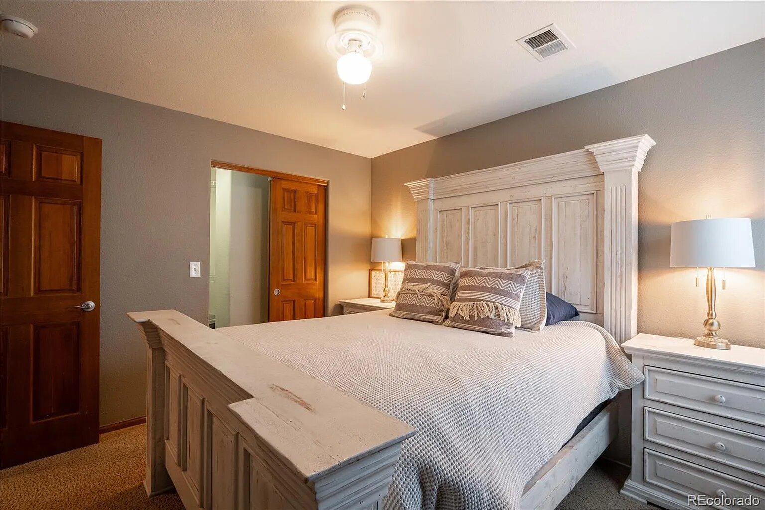 Drift off in your elegant master bedroom featuring a custom wood headboard, plush bedding, and warm bedside lighting for ultimate comfort.
