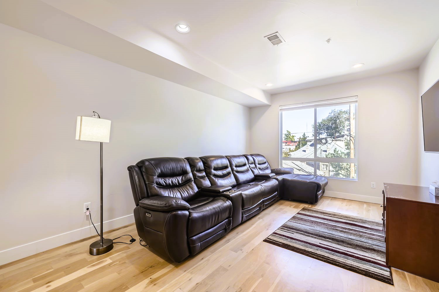 Sink into luxurious leather seating while you watch your favorite shows in this bright, contemporary living space with gleaming hardwood floors.
