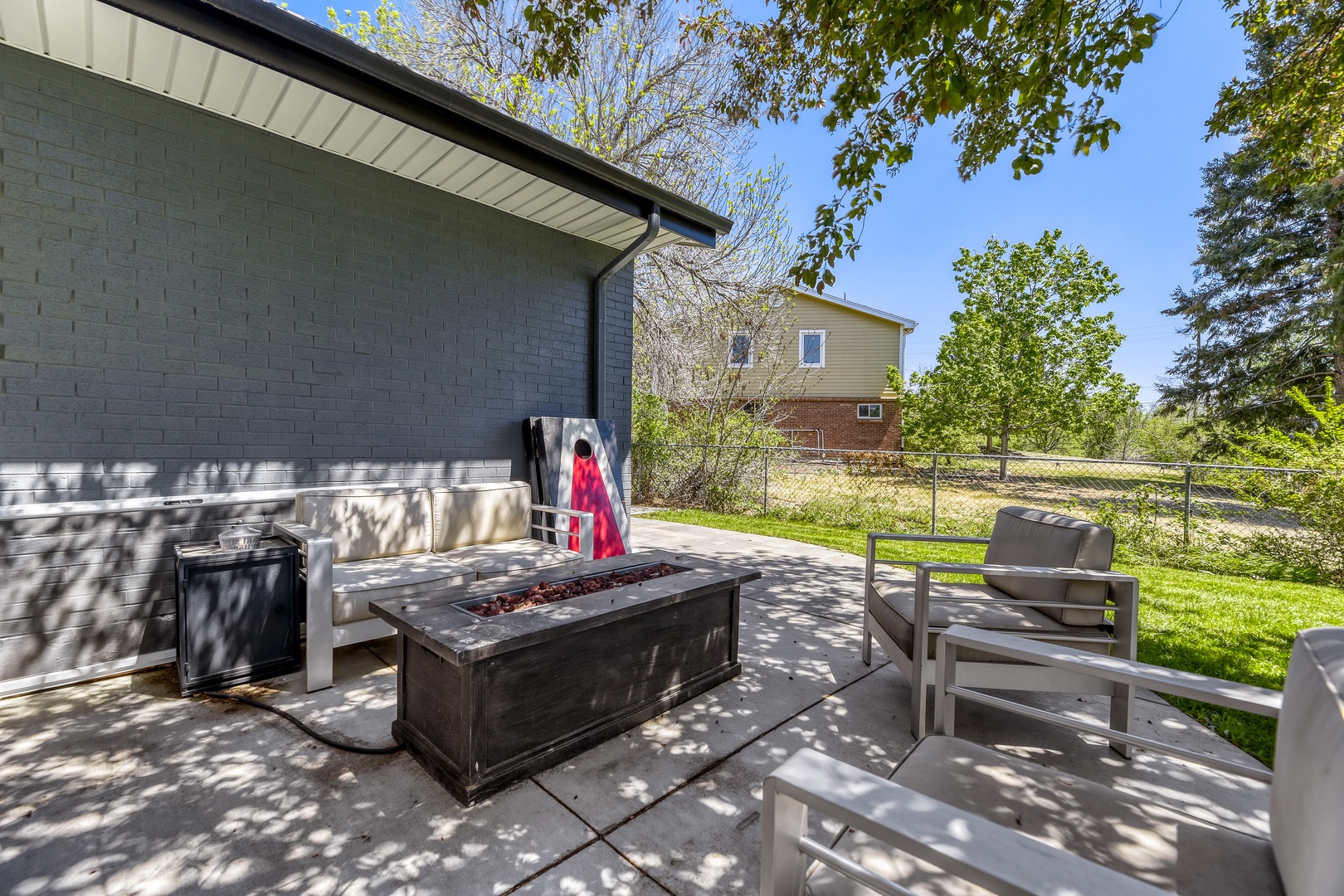 Your private patio features a fire pit and comfortable seating, perfect for relaxing under dappled tree shade and enjoying the peaceful backyard setting.