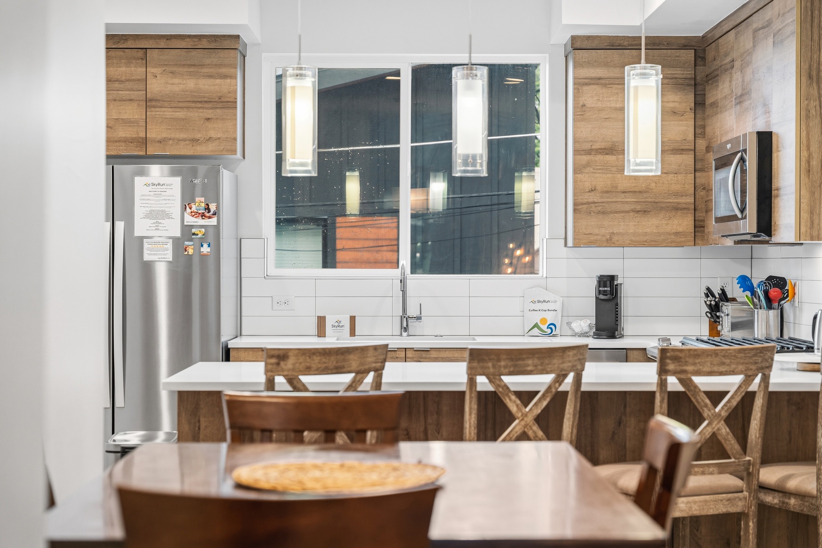 Gather around this bright modern kitchen with warm wood tones, white counters, and a breakfast bar for easy meals together. Stainless appliances and ample seating make cooking and entertaining effortless.