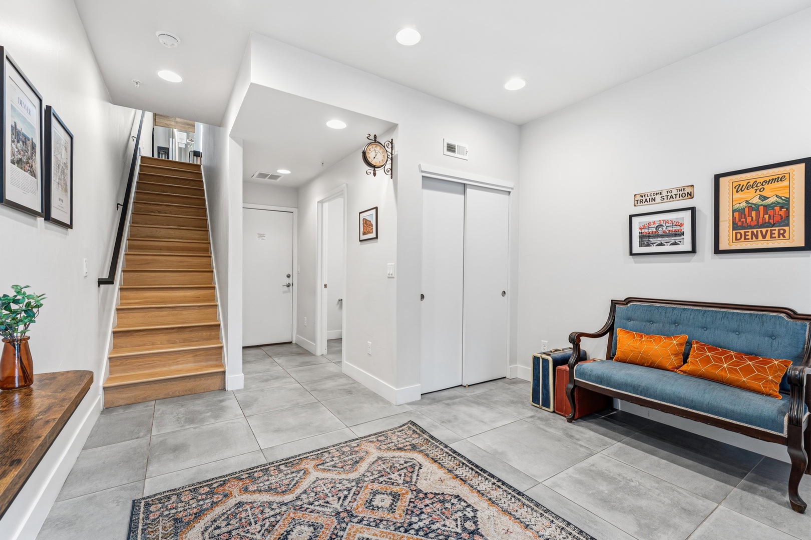 Your welcoming entryway features stylish decor, a cozy seating area, and warm wooden stairs that lead to your private retreat upstairs.