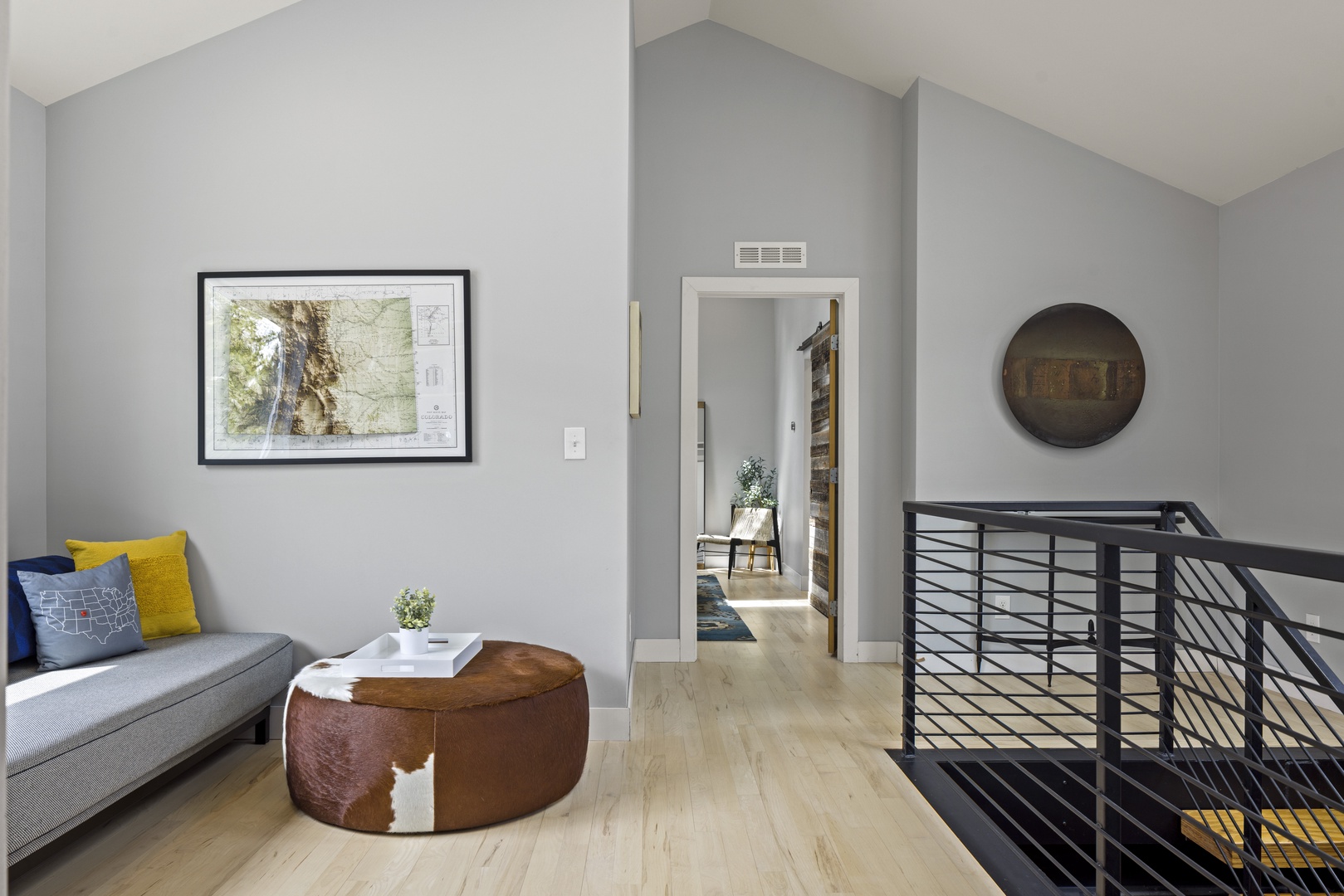 Sink into the plush sofa with colorful pillows and unwind in this stylish upstairs lounge, where modern art and warm wood floors create your perfect retreat.