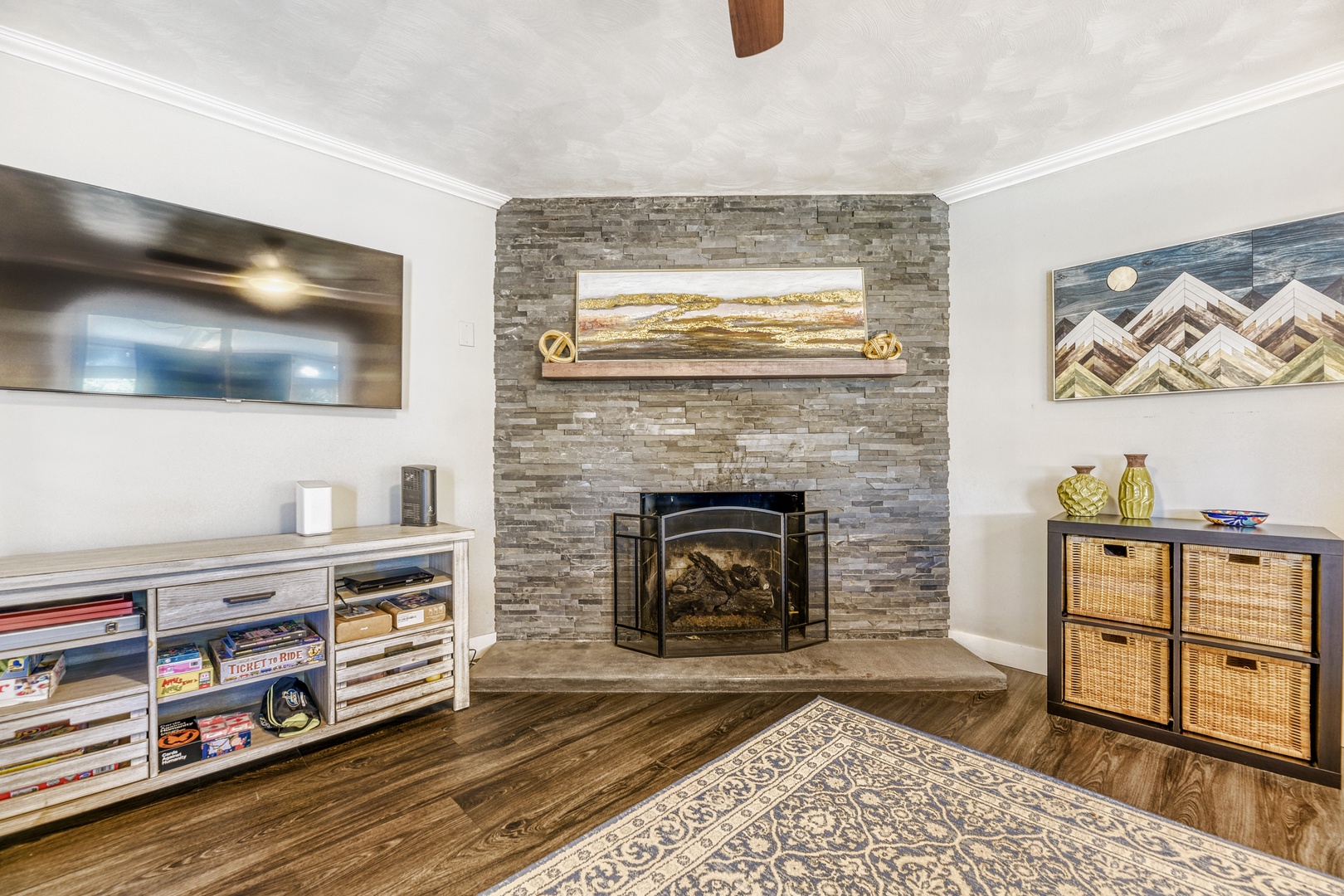 Cozy up in your living room where a beautiful stacked-stone fireplace anchors the space, surrounded by warm wood floors and thoughtful storage for your favorite games and books.