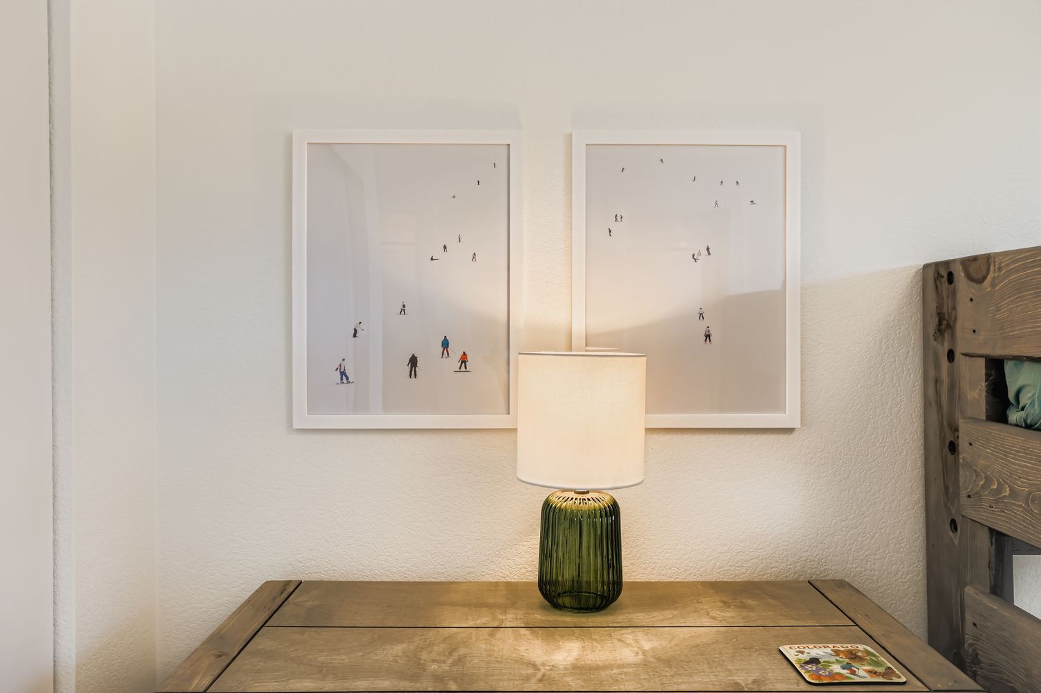 This rustic wooden desk and warm lamp create your perfect workspace, with playful ski art adding alpine charm to the cozy corner.