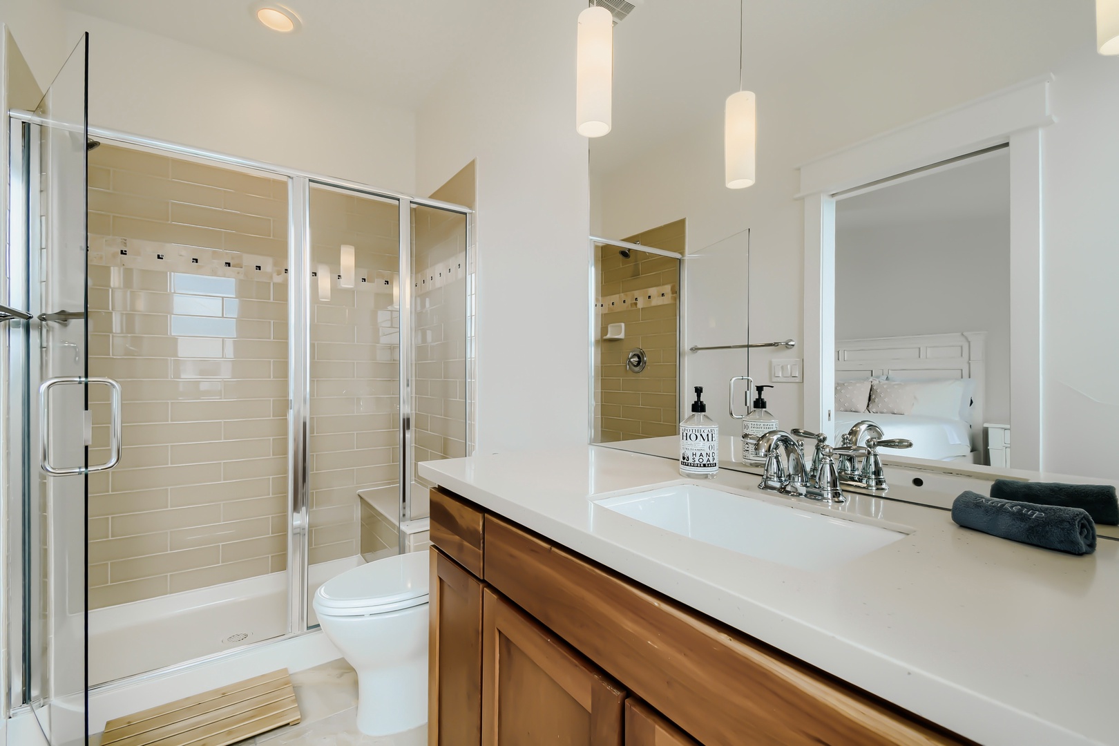 Refresh in your modern, spa-inspired bathroom with sleek tile work, a spacious walk-in shower, and warm wood vanity. Soft pendant lighting and crisp white surfaces create a calming retreat.