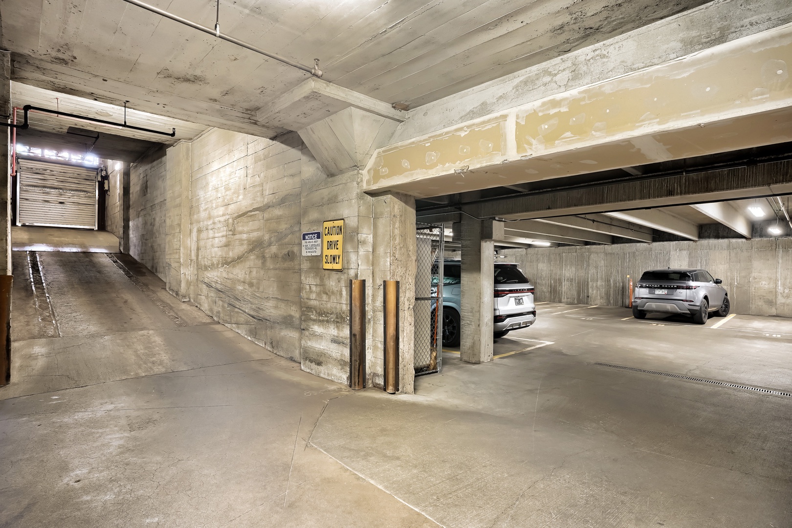 Covered parking garage with concrete construction and ample space for vehicles, providing secure and convenient on-site parking during your stay.