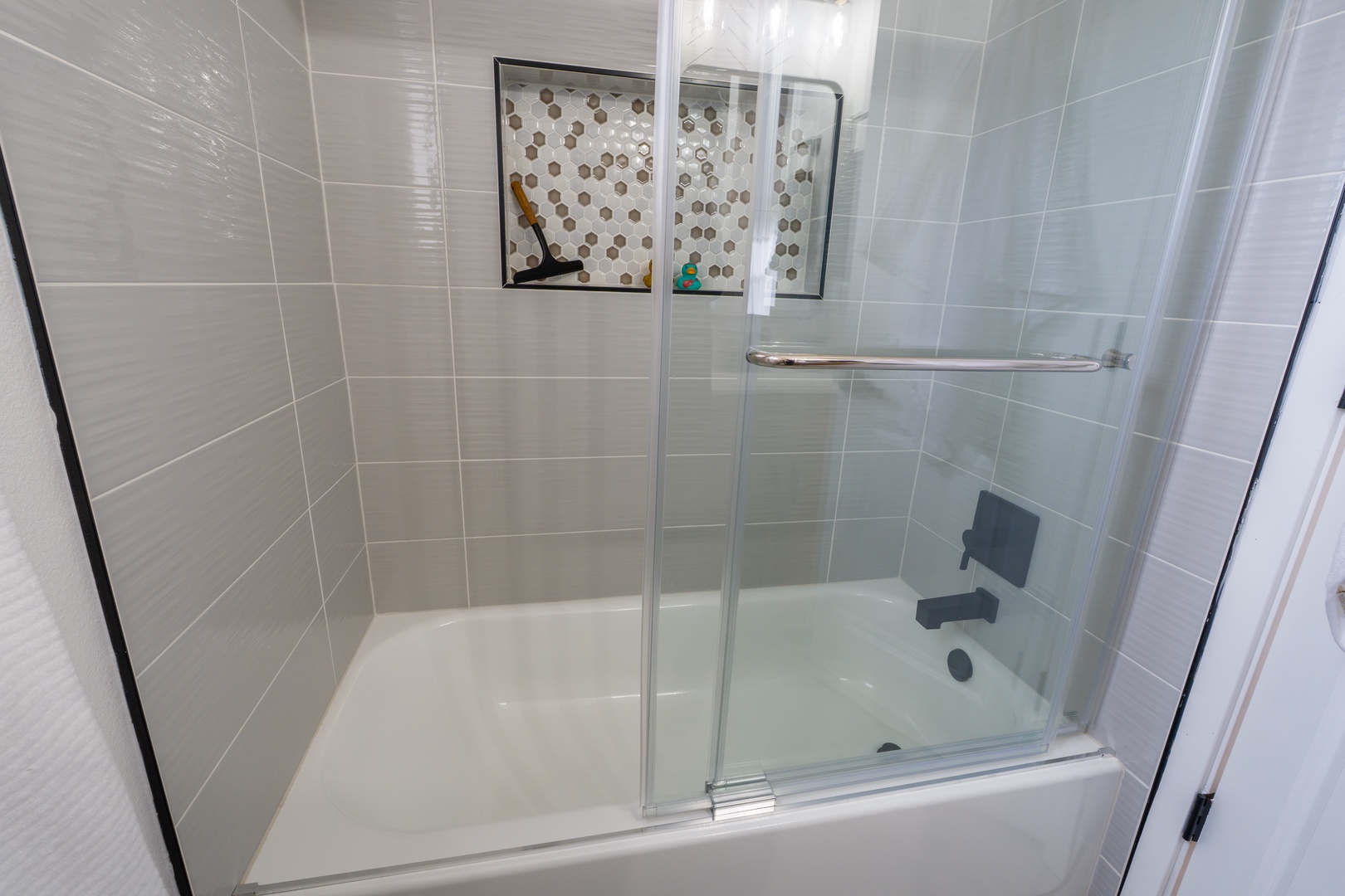 Step into your sleek bathroom featuring a spacious glass-enclosed tub and shower combo, perfect for unwinding after exploring.