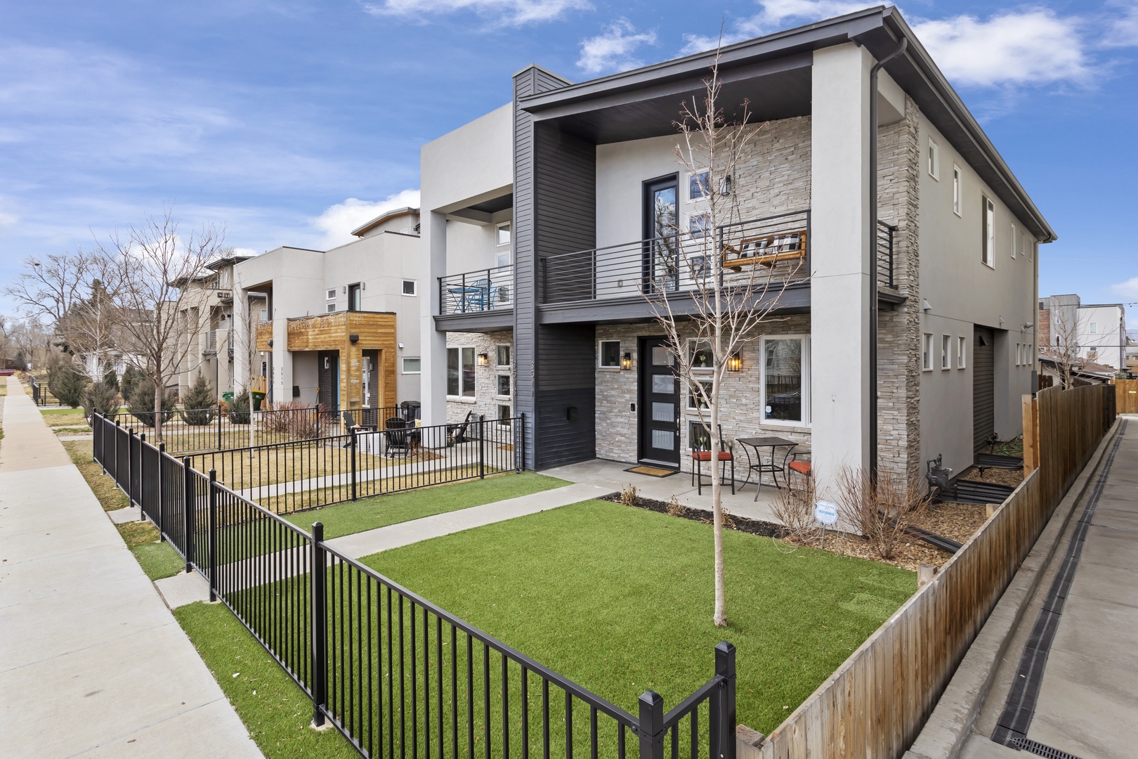 Modern two-story home featuring contemporary architecture with stone accents and private fenced yard in peaceful residential neighborhood.