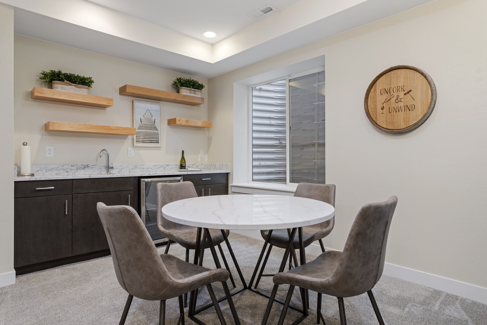 Gather around your elegant marble dining table in this chic space, featuring modern kitchenette with floating shelves and stylish decor.