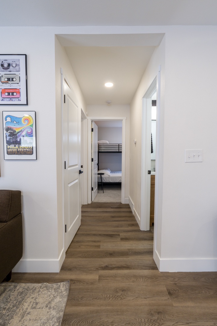Step through this bright hallway where warm wood floors lead you to comfortable bedrooms, each thoughtfully designed for your restful stay.