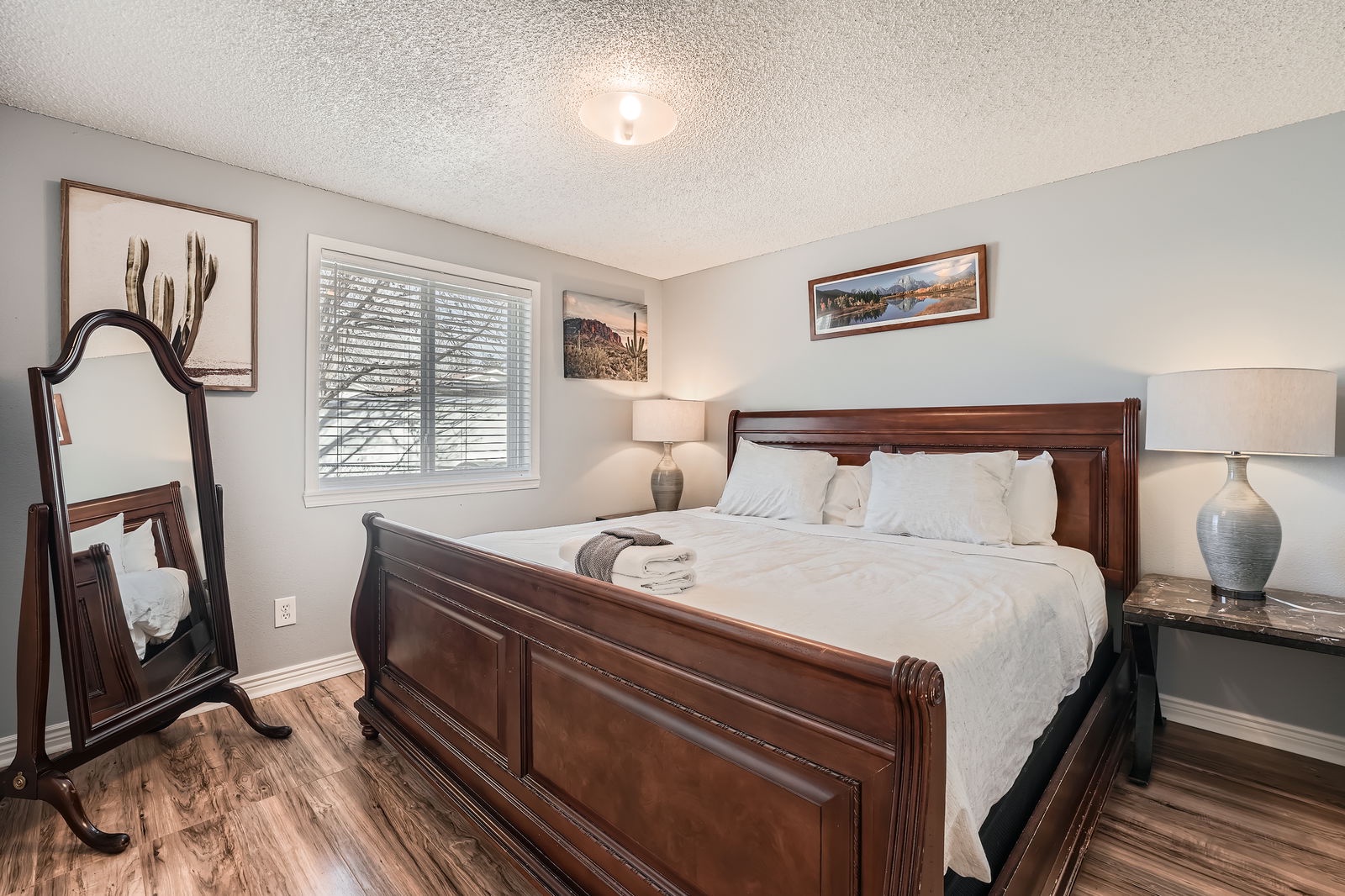 Sink into crisp linens on your elegant wooden sleigh bed, surrounded by warm desert artwork and soft lamp lighting.