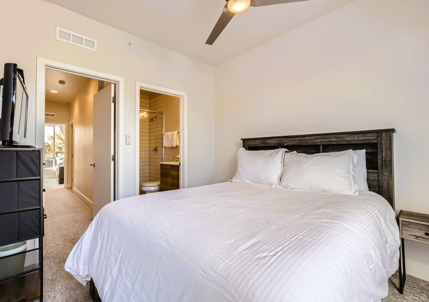 Rest peacefully in your master bedroom with crisp linens, rustic wood headboard, and ensuite bathroom just steps away.