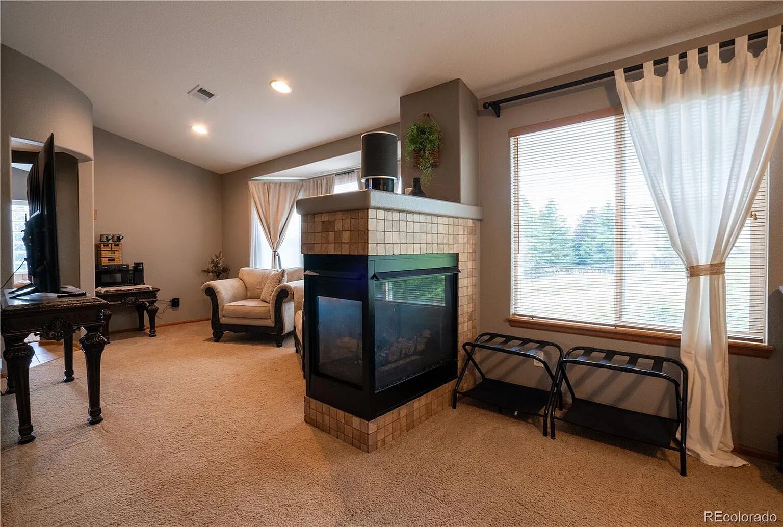 Cozy up in this spacious living room where warm carpets meet your feet and a stunning fireplace creates the perfect ambiance for relaxing evenings.