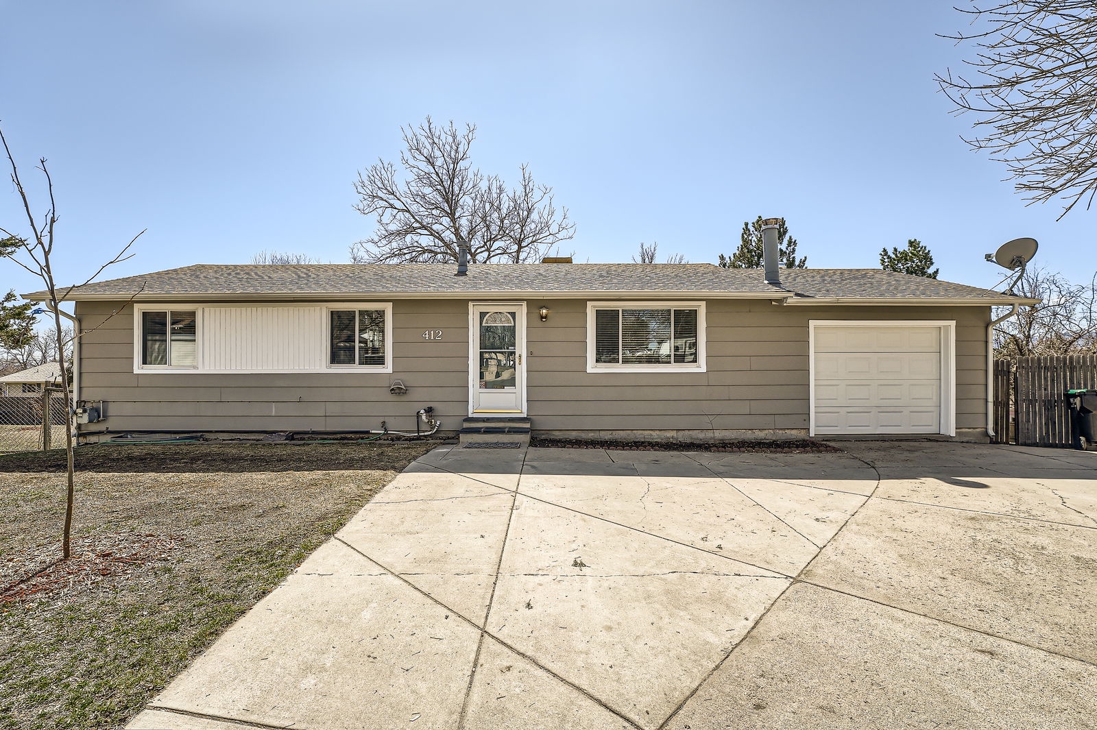 Charming single-story home featuring a welcoming front entrance and spacious driveway with attached garage for convenient parking.