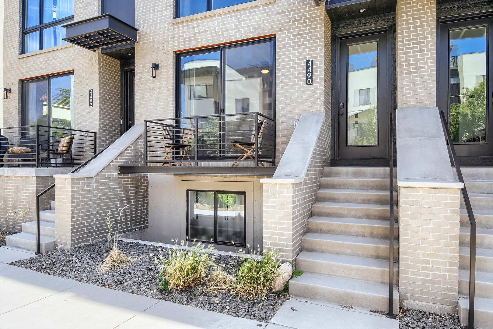 Modern brick townhome exterior featuring private terrace seating, unit 420, with clean architectural lines and garden landscaping in a contemporary residential community.