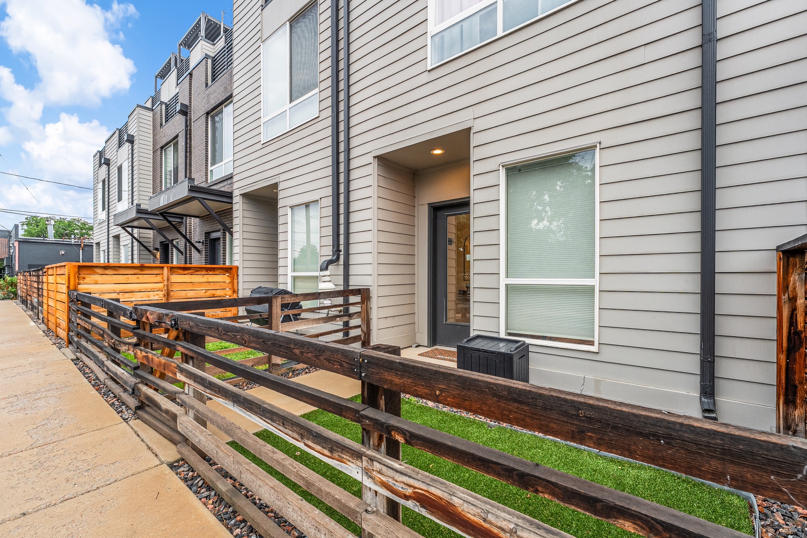 Modern townhome row featuring private patio spaces and welcoming front entrances along a quiet residential street.