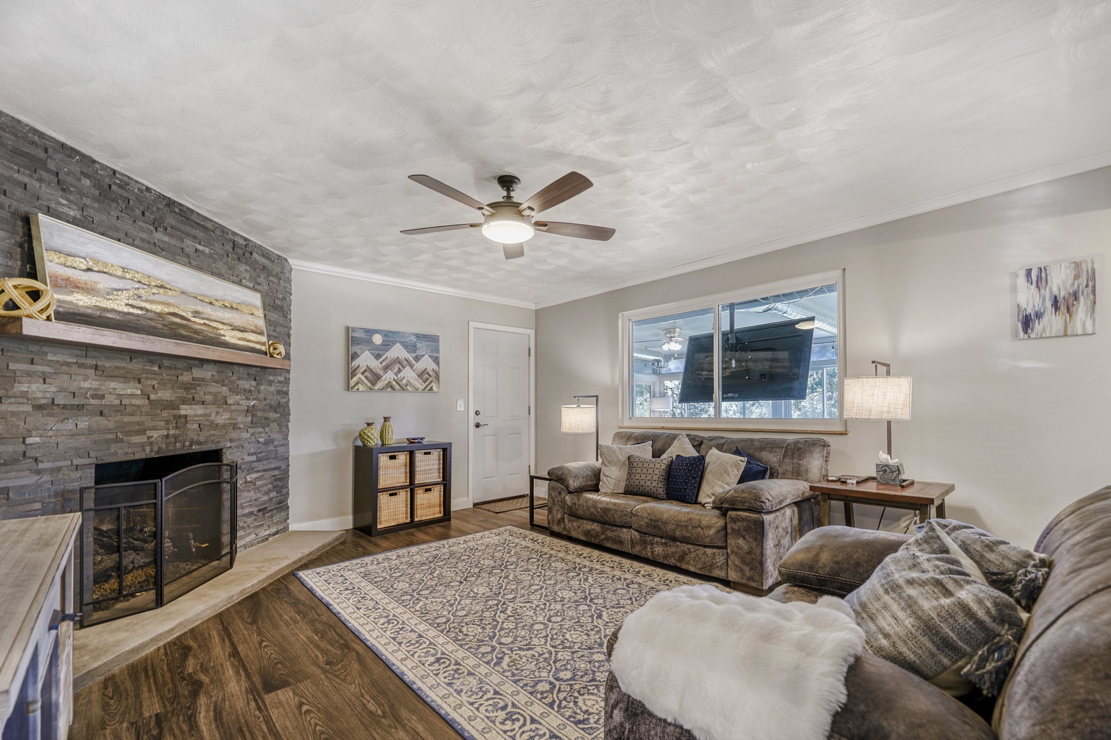 Sink into plush sofas before your stone fireplace, where rustic charm meets modern comfort. Natural light and warm textures create your perfect gathering space.