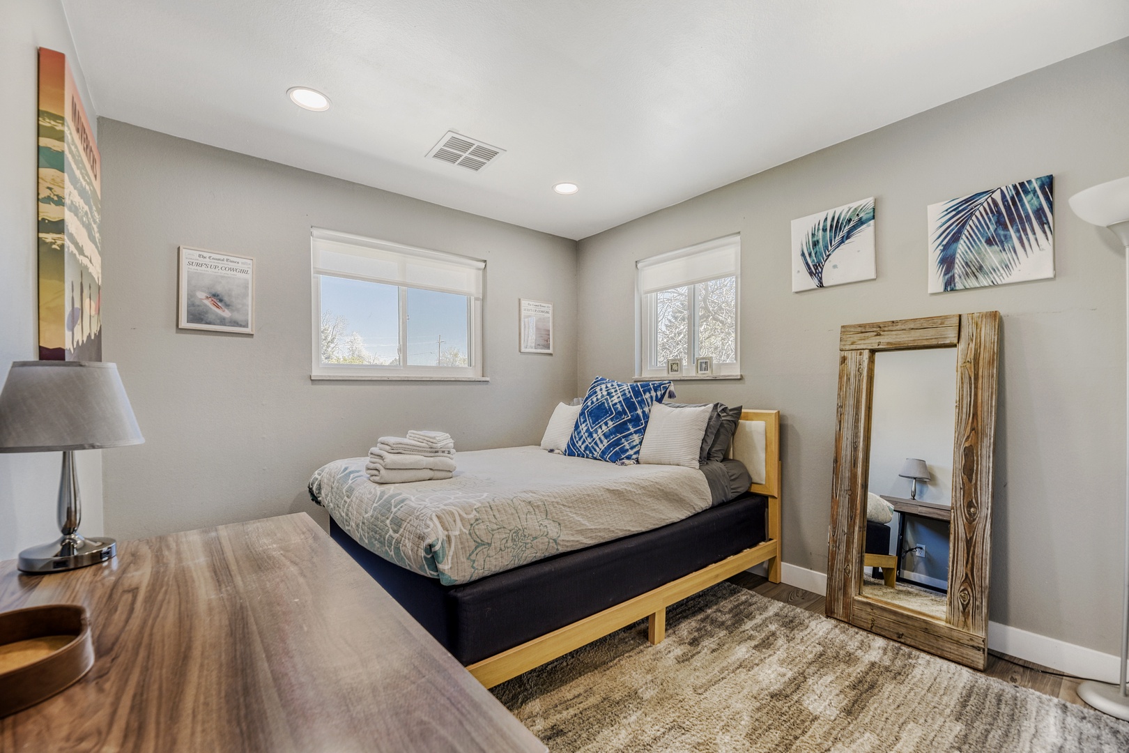 Your cozy bedroom awaits with a plush bed, fresh linens, and coastal décor. Natural light streams through dual windows, while a rustic mirror and calming palette create your perfect retreat.