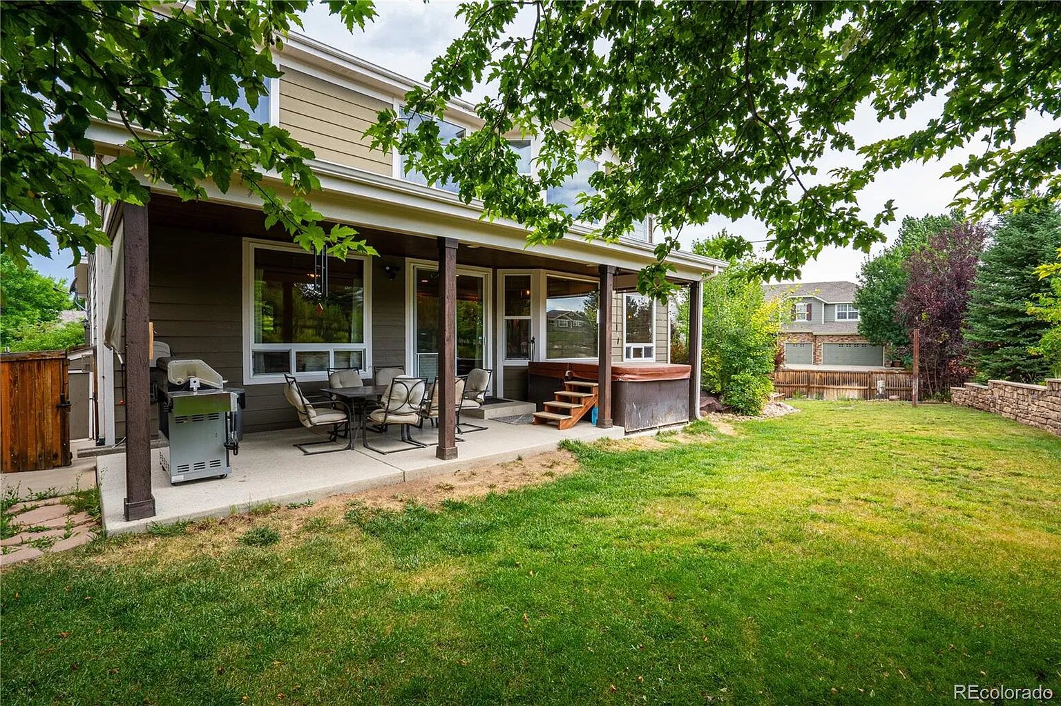 Relax on your private covered patio with outdoor seating, BBQ grill, and hot tub, all surrounded by lush landscaping and mature trees.