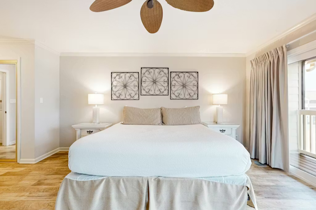 Drift off in your serene coastal bedroom, where soft linens and a breezy ceiling fan create the perfect haven for restful nights.