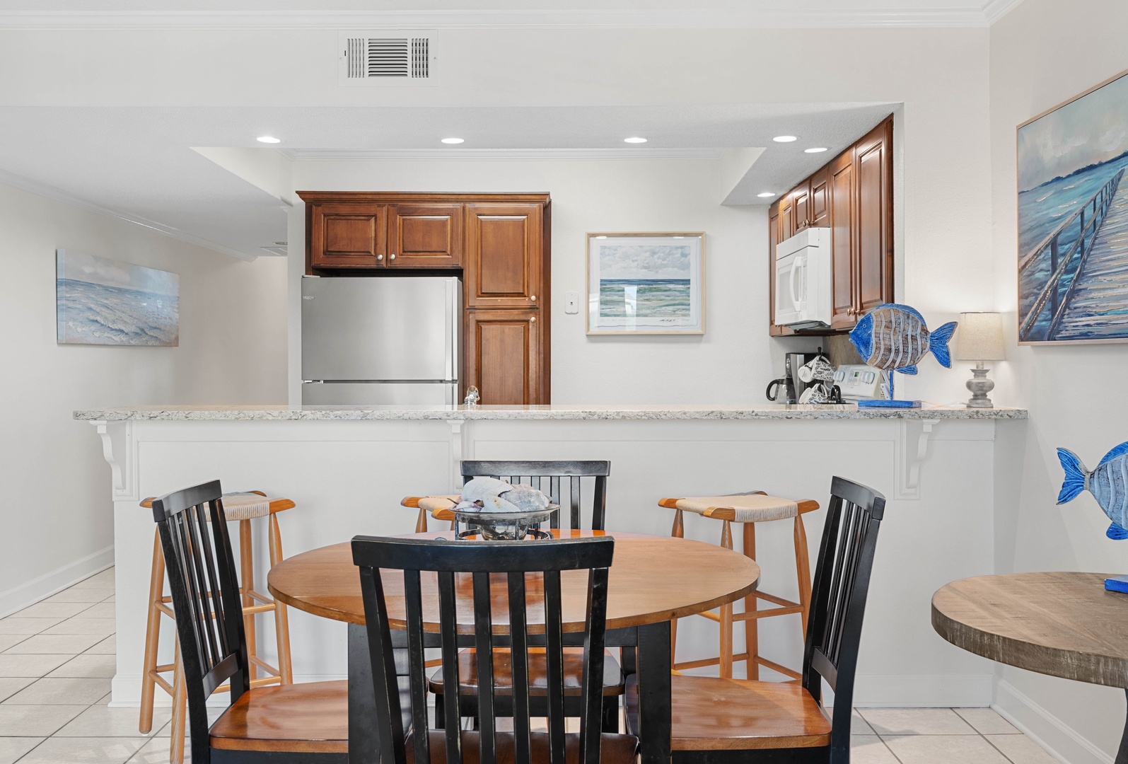 Gather around your spacious dining table while meals simmer in the fully-equipped kitchen, where ocean-inspired artwork creates a serene coastal atmosphere.