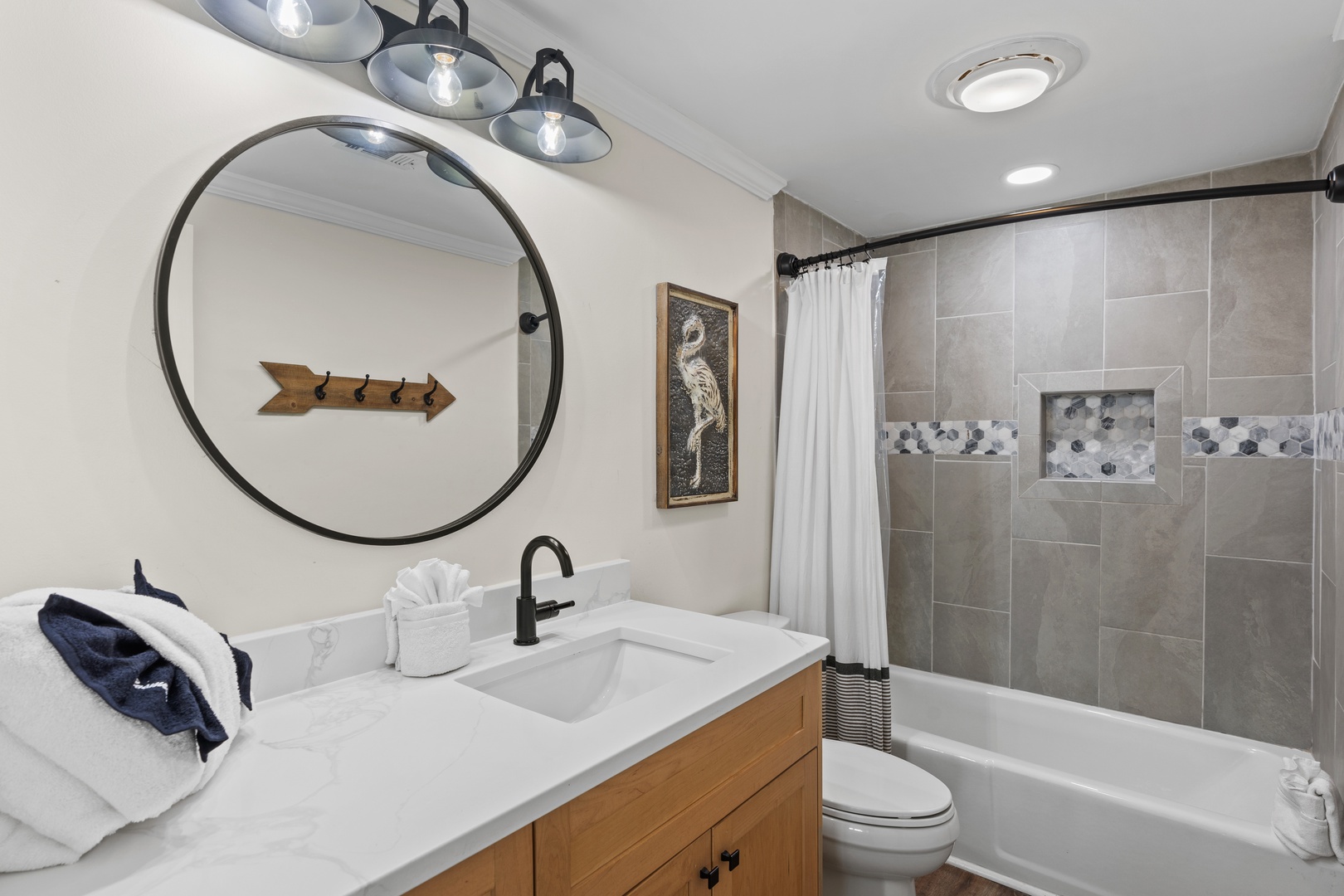 Refresh in your modern bathroom featuring stylish lighting, spacious shower-tub combo, and thoughtful touches like fluffy towels.