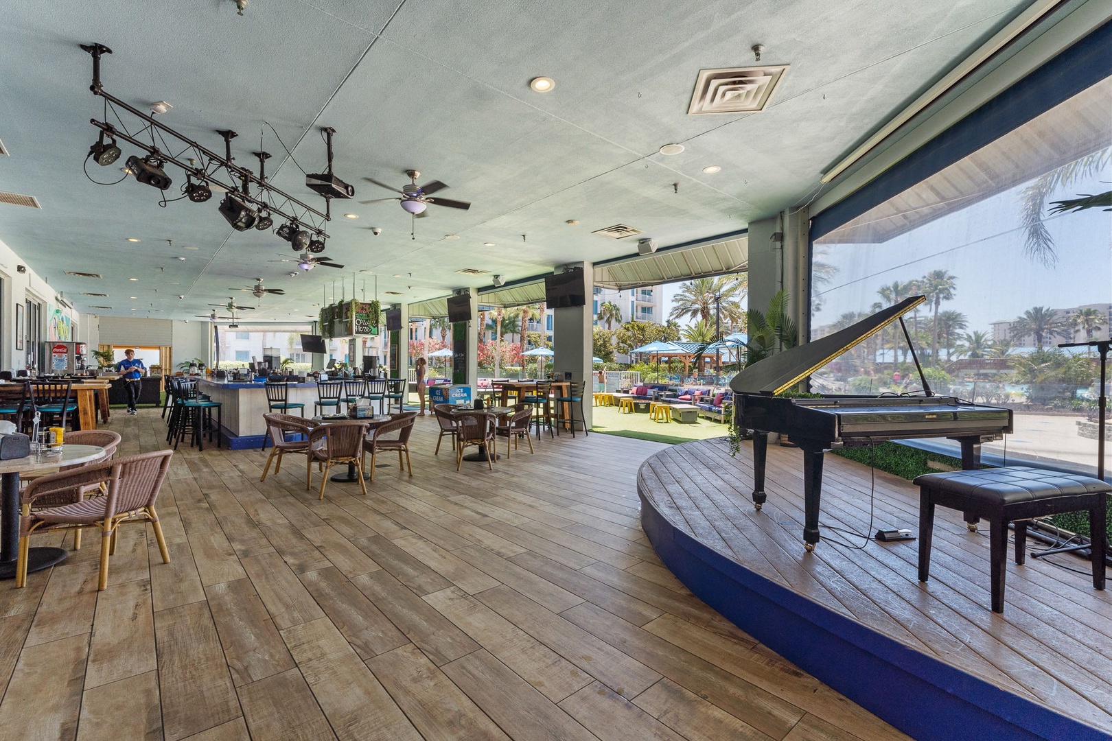 Elegant dining space featuring a grand piano, tropical views, and open-air design where you can savor meals surrounded by palms and poolside ambiance.