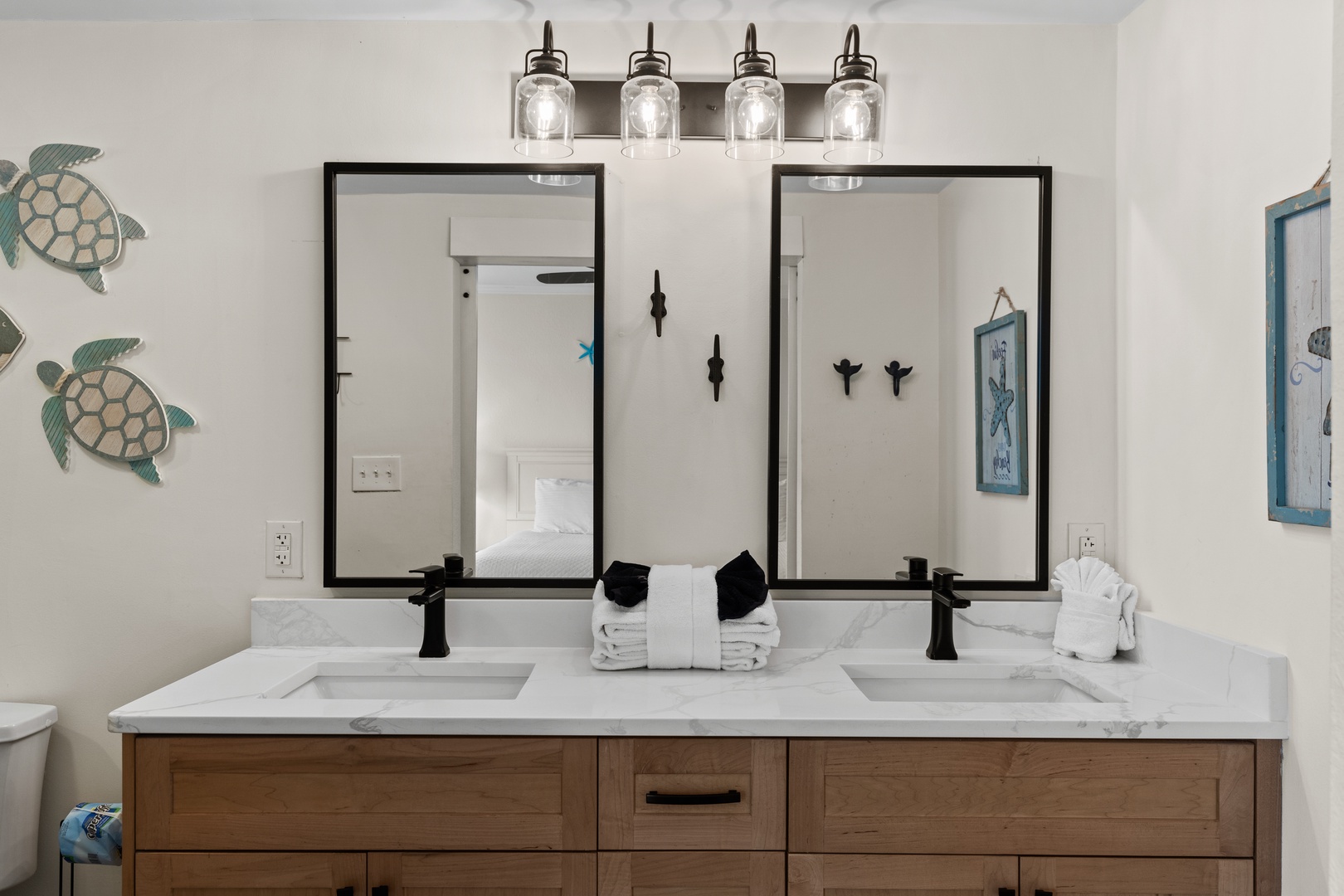 Your coastal-themed bathroom awaits with dual sinks, elegant lighting, and charming sea turtle décor—perfect for sharing your morning routine.
