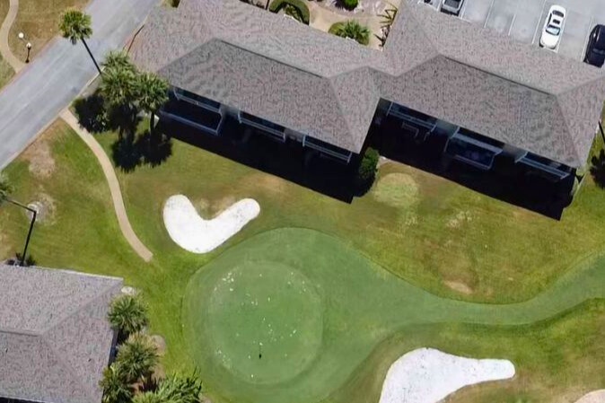 Aerial view of property featuring miniature golf course with winding greens and sand traps in landscaped grounds.