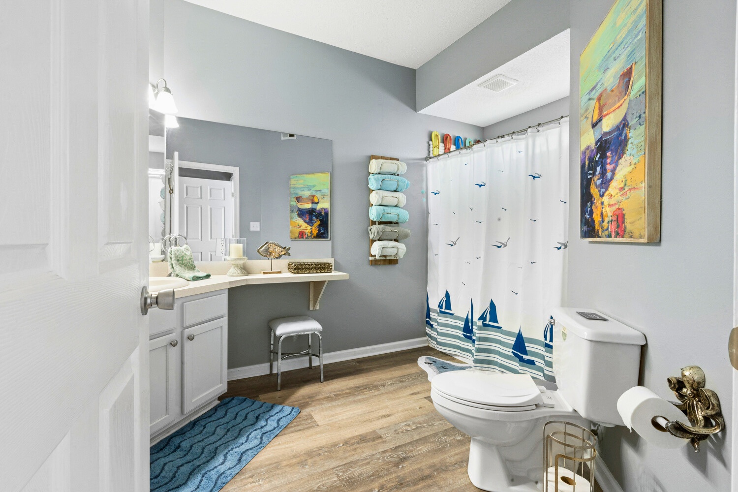 Your private bathroom features coastal charm with nautical artwork, plush towels, and a relaxing shower after beach days.