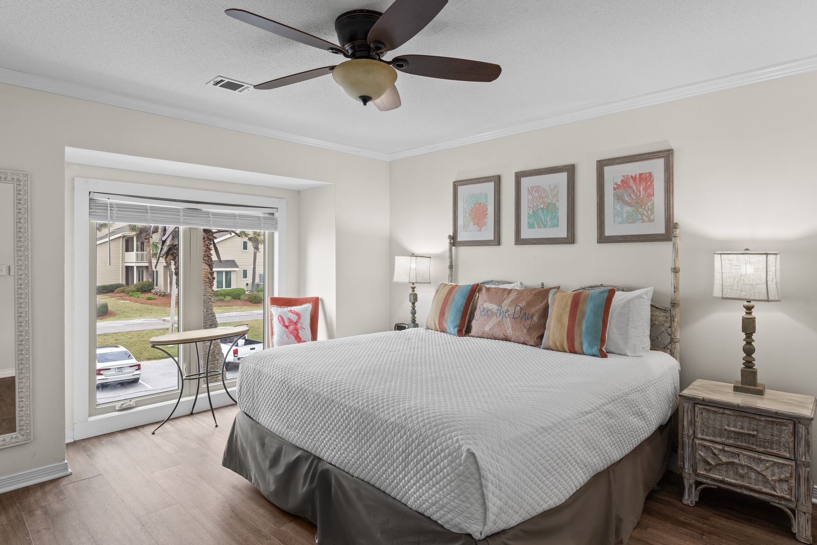 Drift into peaceful sleep in this cozy bedroom, where colorful coastal artwork and gentle ceiling fan breezes create your perfect retreat.