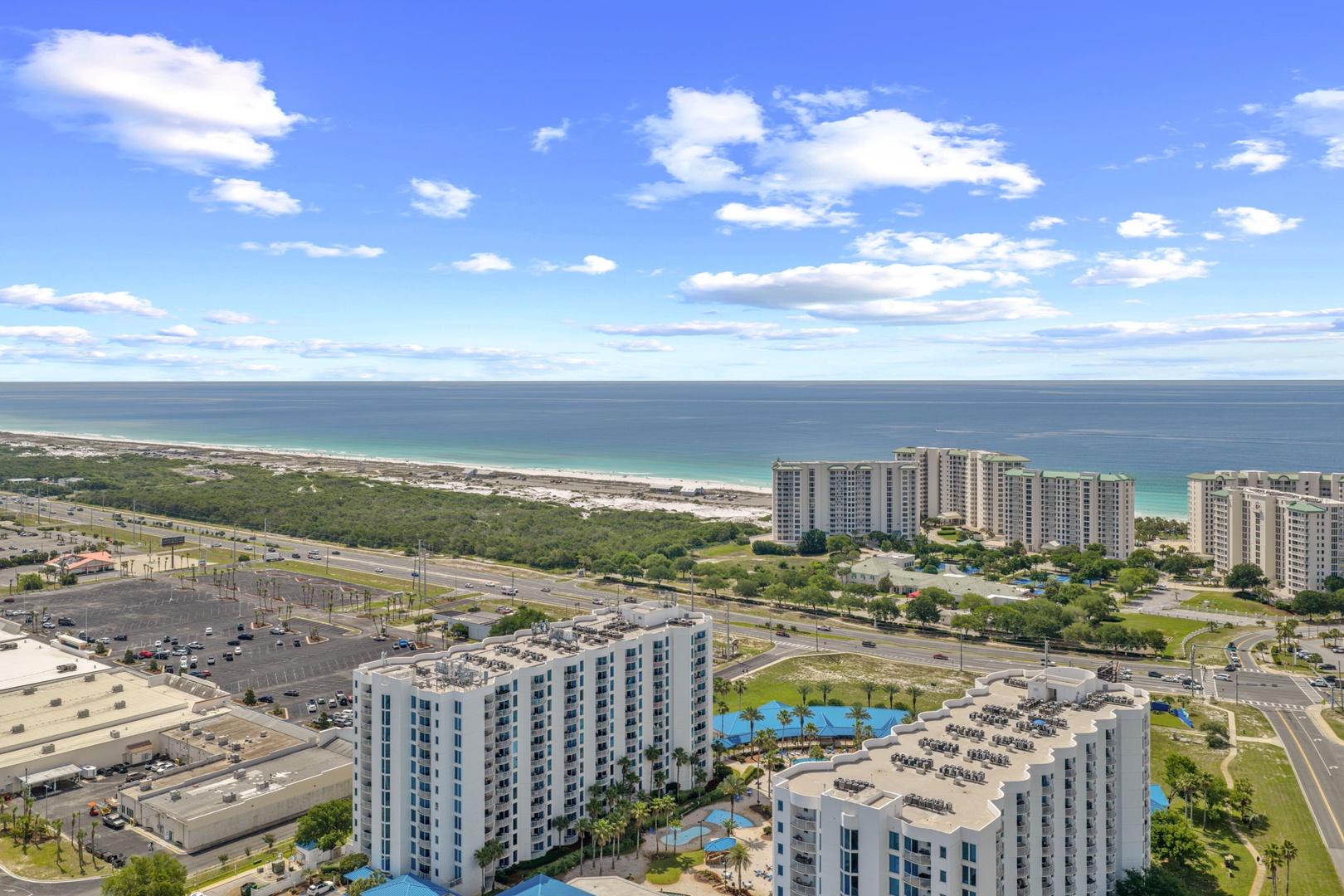 Aerial view of a beachfront vacation rental complex featuring pools, palm trees, and direct access to white sand beaches along the Gulf Coast.