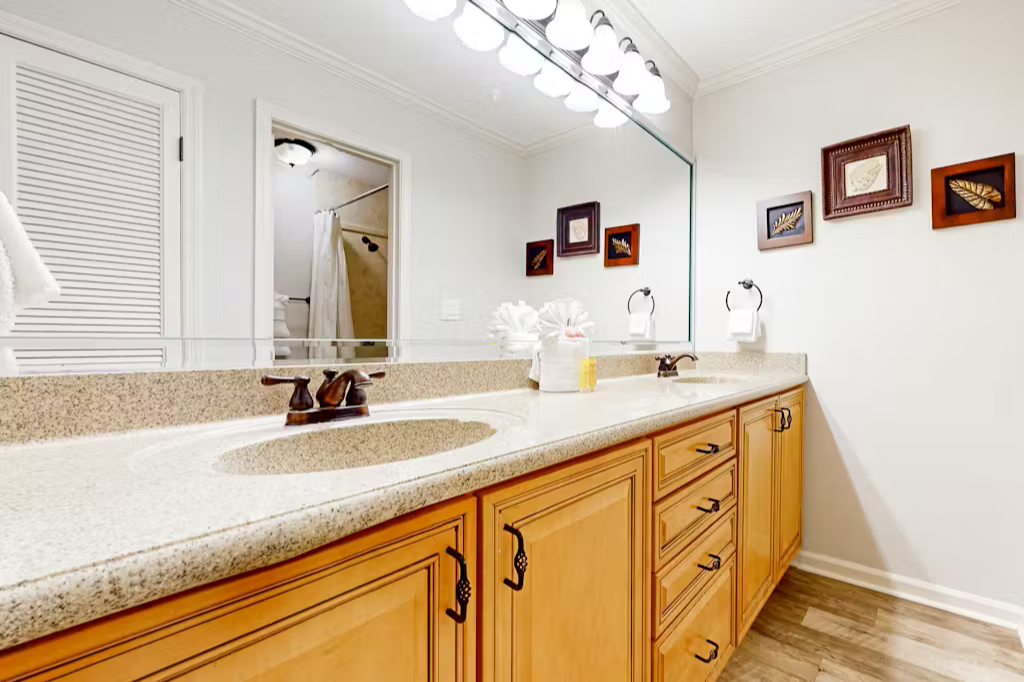 Refresh in your spacious en-suite with dual sinks, gleaming countertops, and warm wood cabinetry designed for your comfort and convenience.