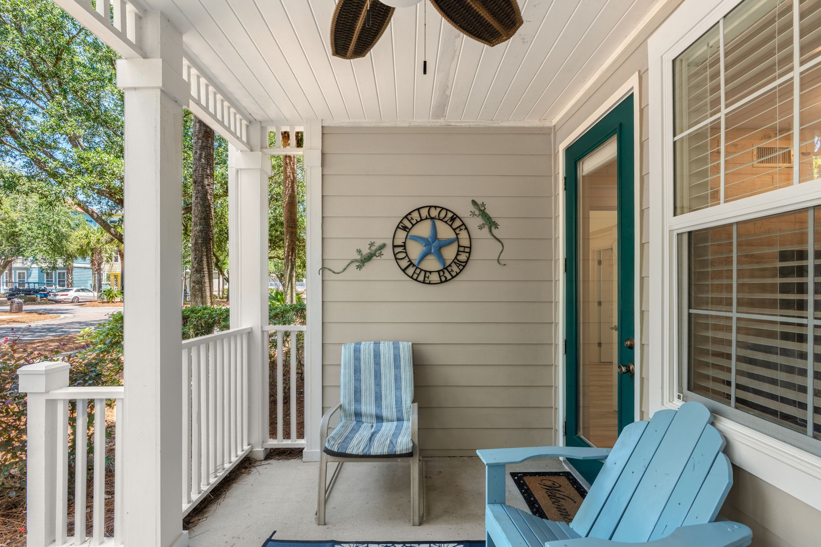 A charming front porch welcomes guests with coastal seating, greenery, and a personalized star sign marking the entrance to this cozy coastal home.